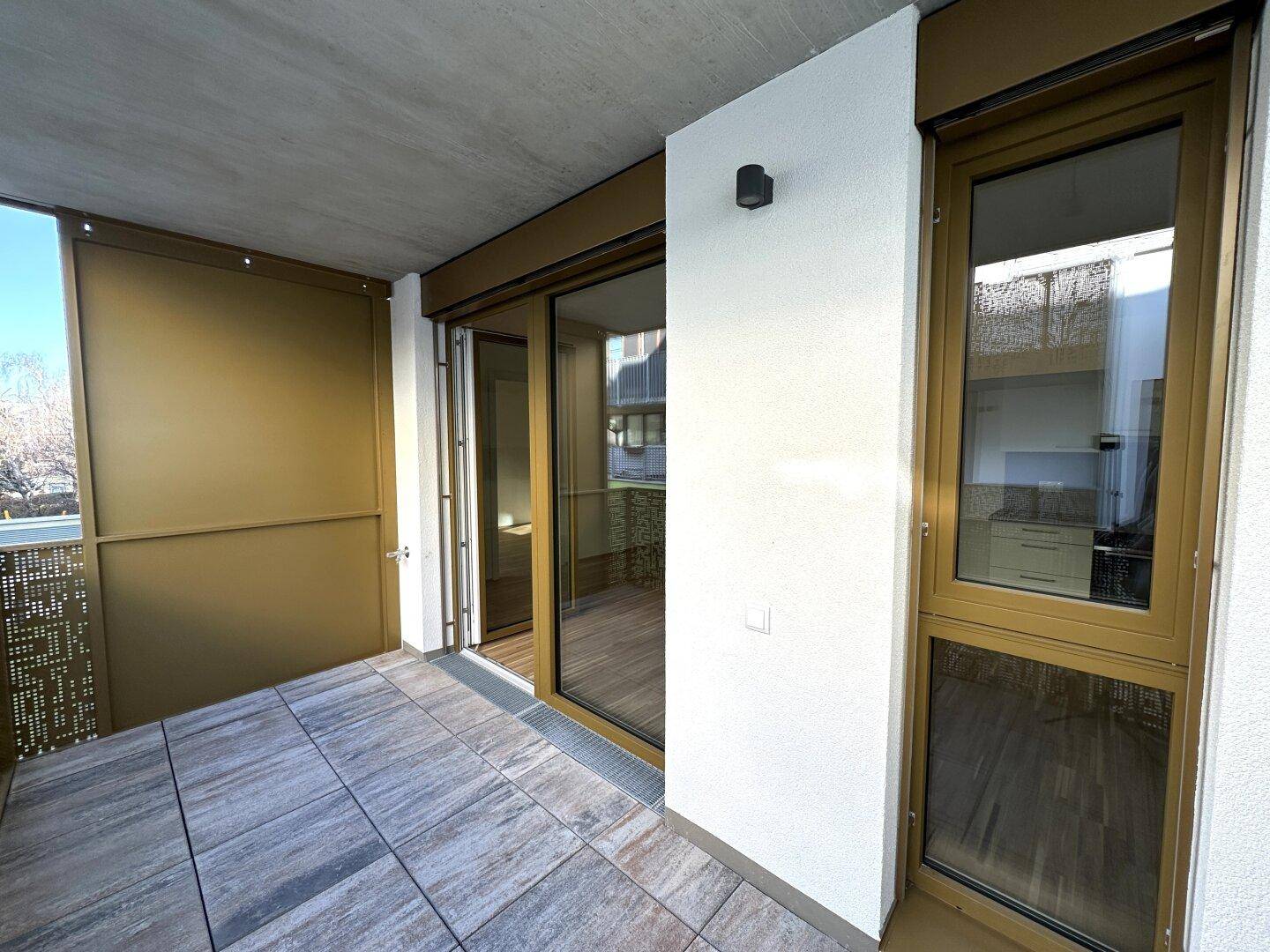 Geräumiger Balkon mit Fliesenboden und großen Schiebetüren, die den Innenraum mit dem Außenbereich verbinden.