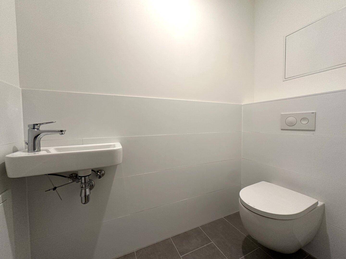 Kleines Gäste-WC mit wandhängender Toilette und kompaktem Waschbecken, modern und funktional gestaltet.
