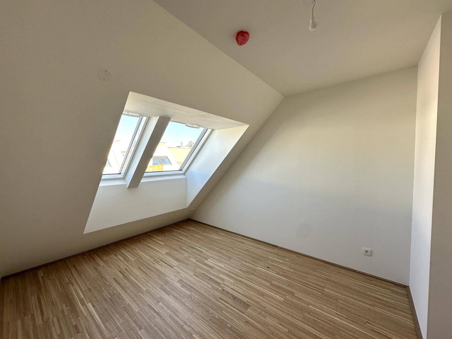 Schlafzimmer mit Parkettboden, Dachschrägen und einem großen Dachfenster für viel Licht.