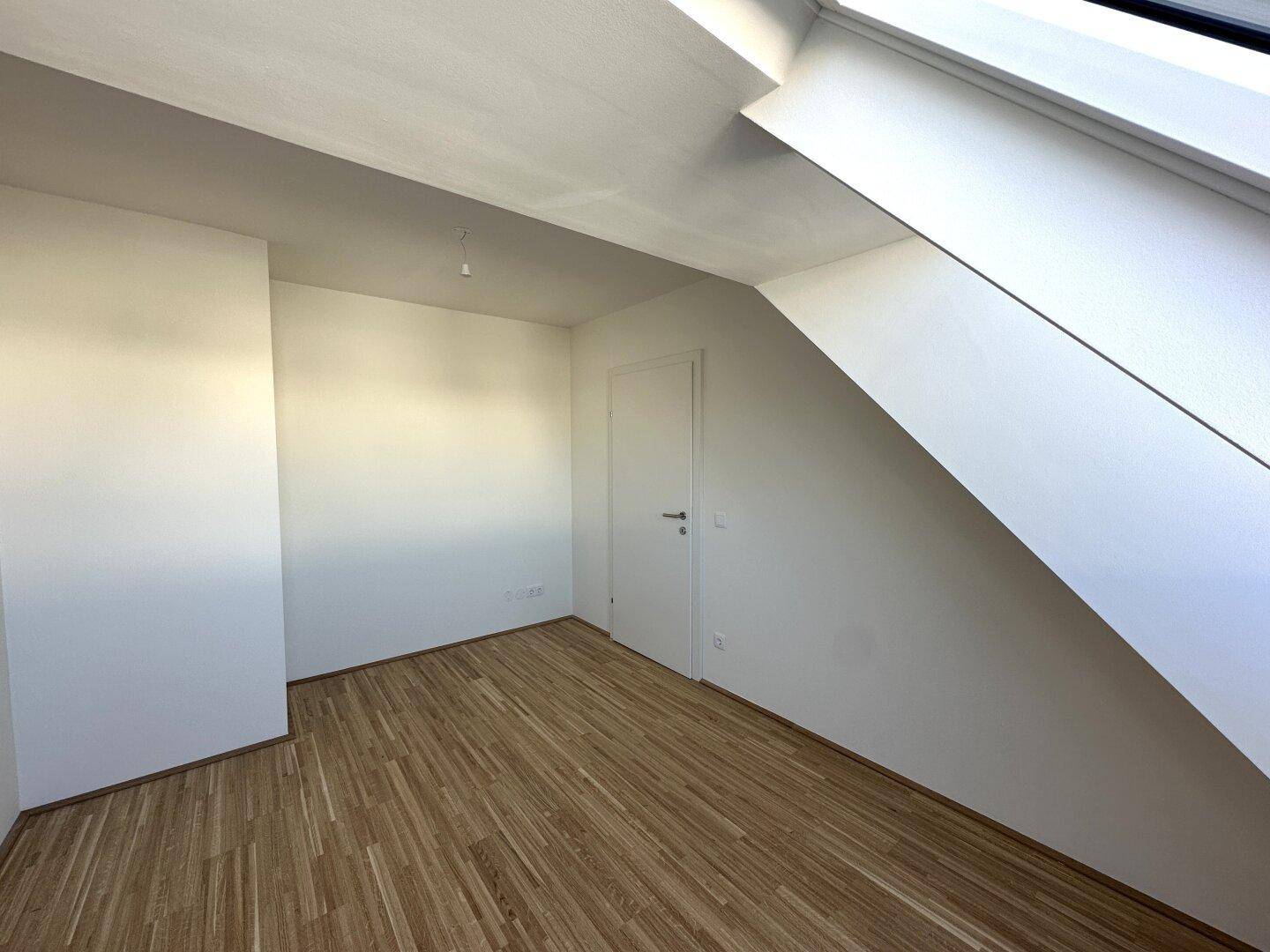 Helles Schlafzimmer mit Parkettboden und Dachschräge, ideal für ein gemütliches Ambiente.