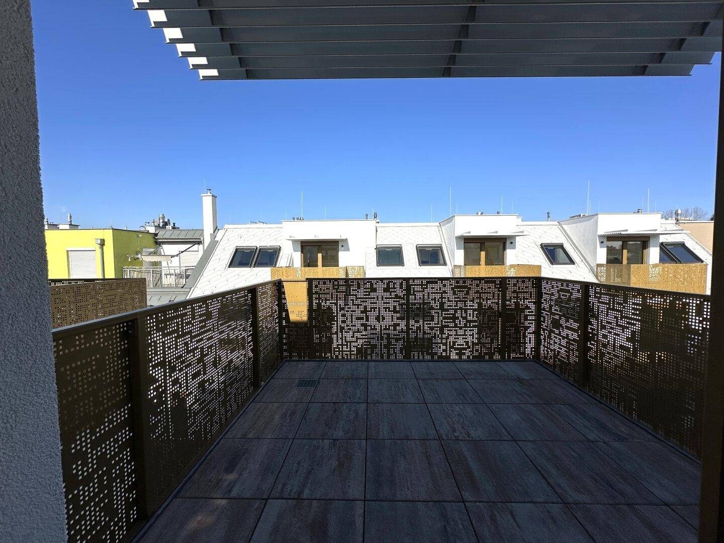 Geräumige Dachterrasse mit modernem Geländer und Blick über die Dächer der Stadt.