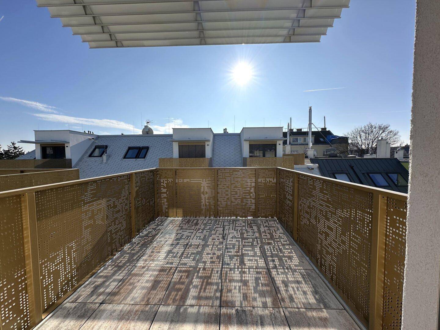 Sonnige Dachterrasse mit modernem Metallgeländer und weitem Blick über die Umgebung.