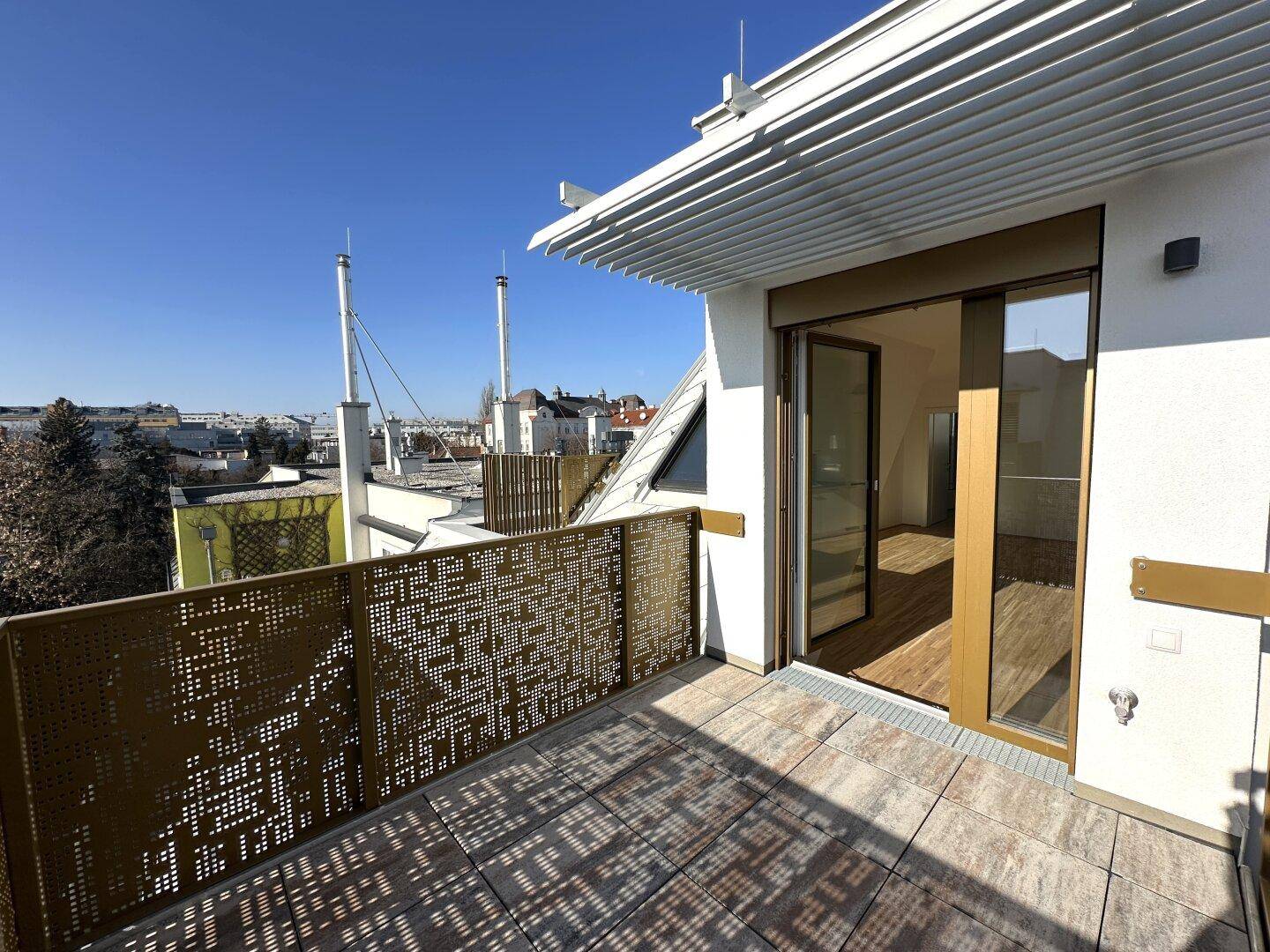 Große Dachterrasse mit Schiebetürzugang und Blick auf die städtische Skyline.