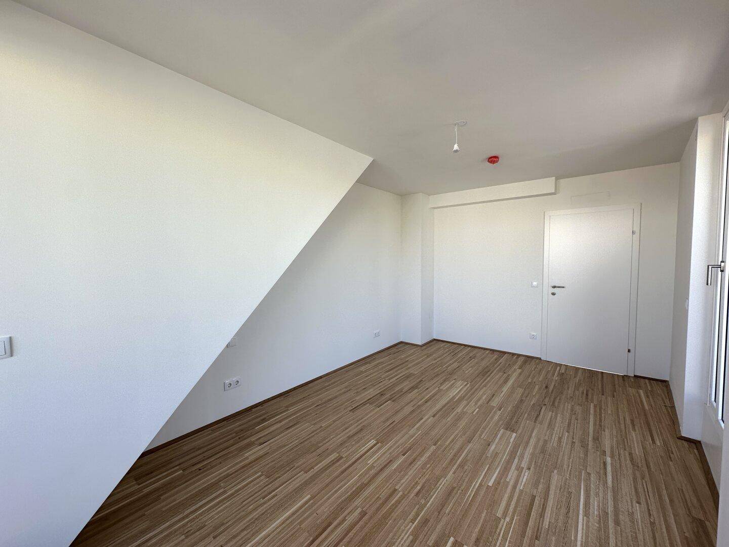 Geräumiges Schlafzimmer mit Parkettboden, Dachschräge und viel Tageslicht.