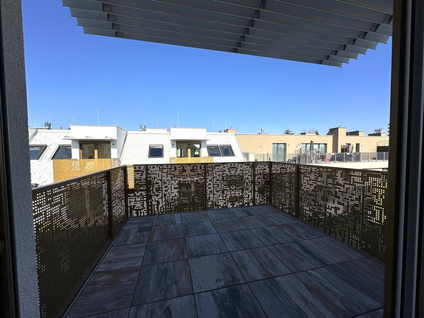 Große, sonnige Dachterrasse mit modernem Metallgeländer und Blick auf die Umgebung.