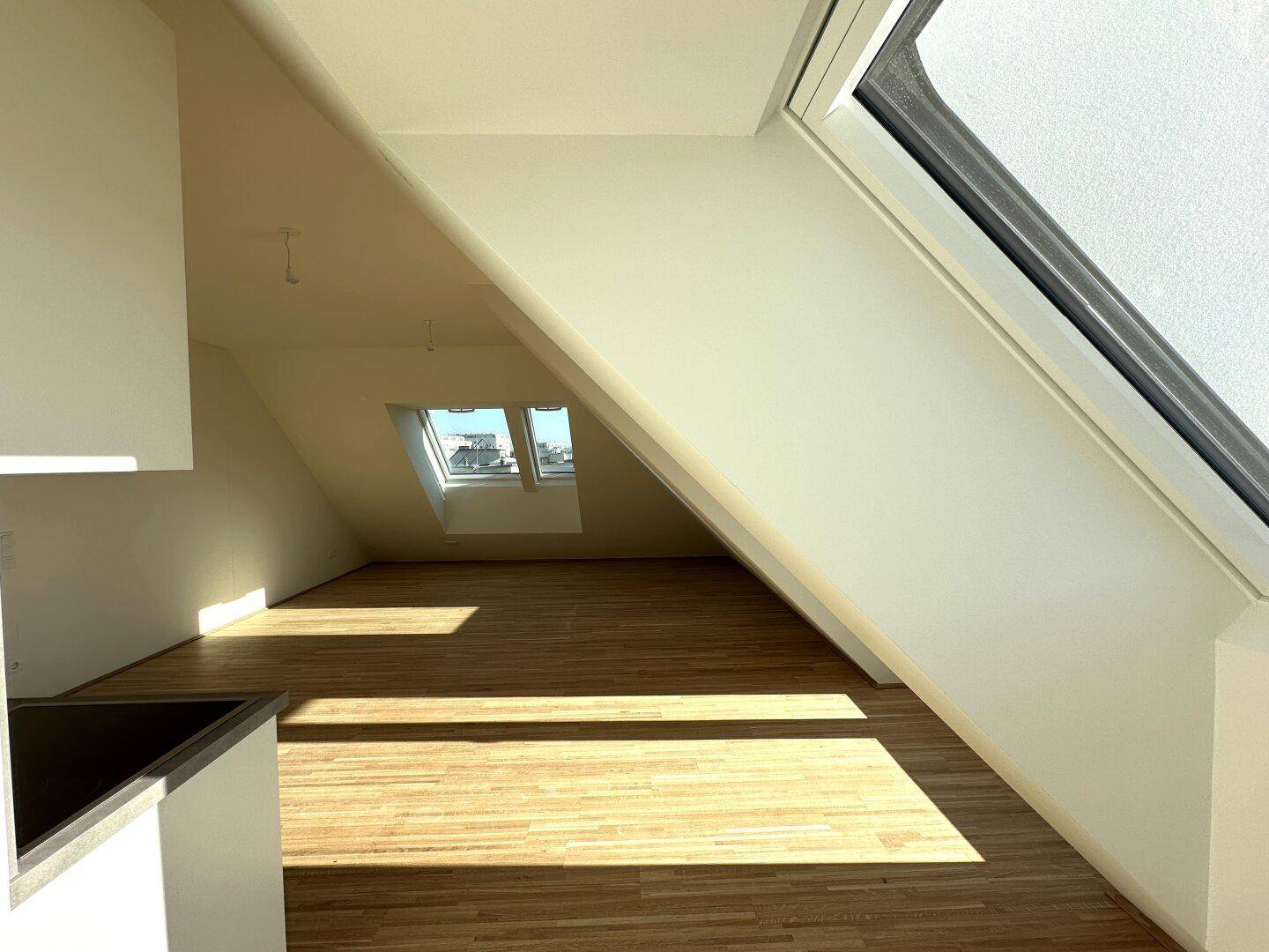 Geräumiger Wohnbereich mit Holzboden, Dachschrägen und viel natürlichem Lichteinfall.