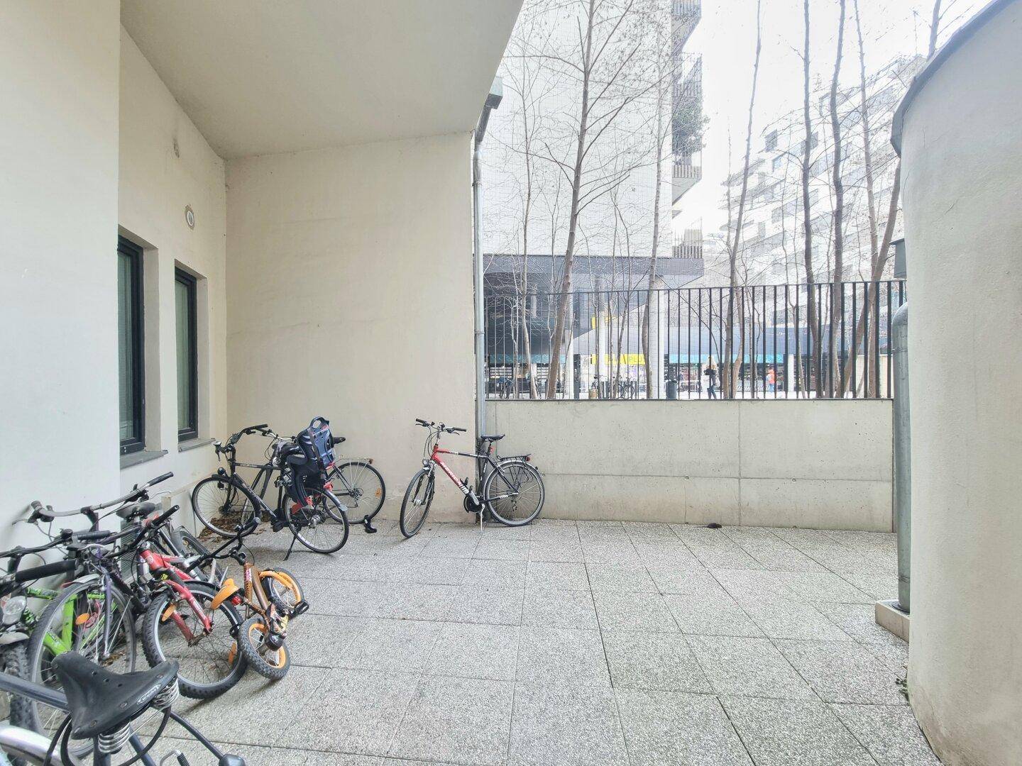 Außenbereich mit Fahrradabstellplätzen und moderner Gebäudearchitektur im Hintergrund.