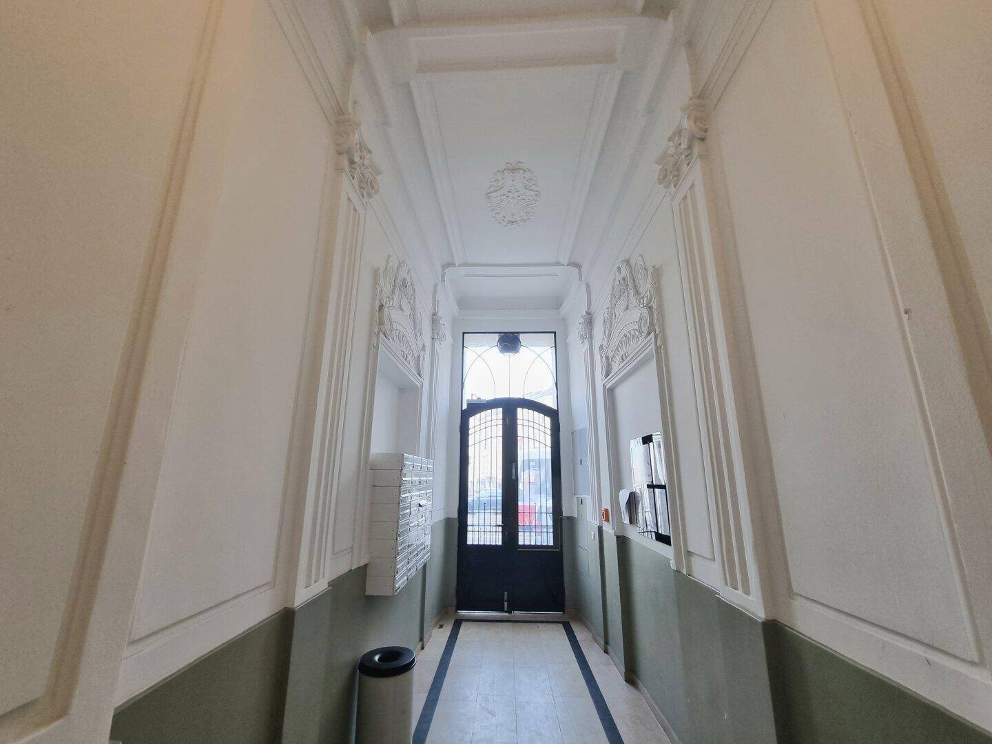 Prunkvoller Eingangsbereich mit Stuckdecke und dekorativer Glastür, die den historischen Charakter betont.
