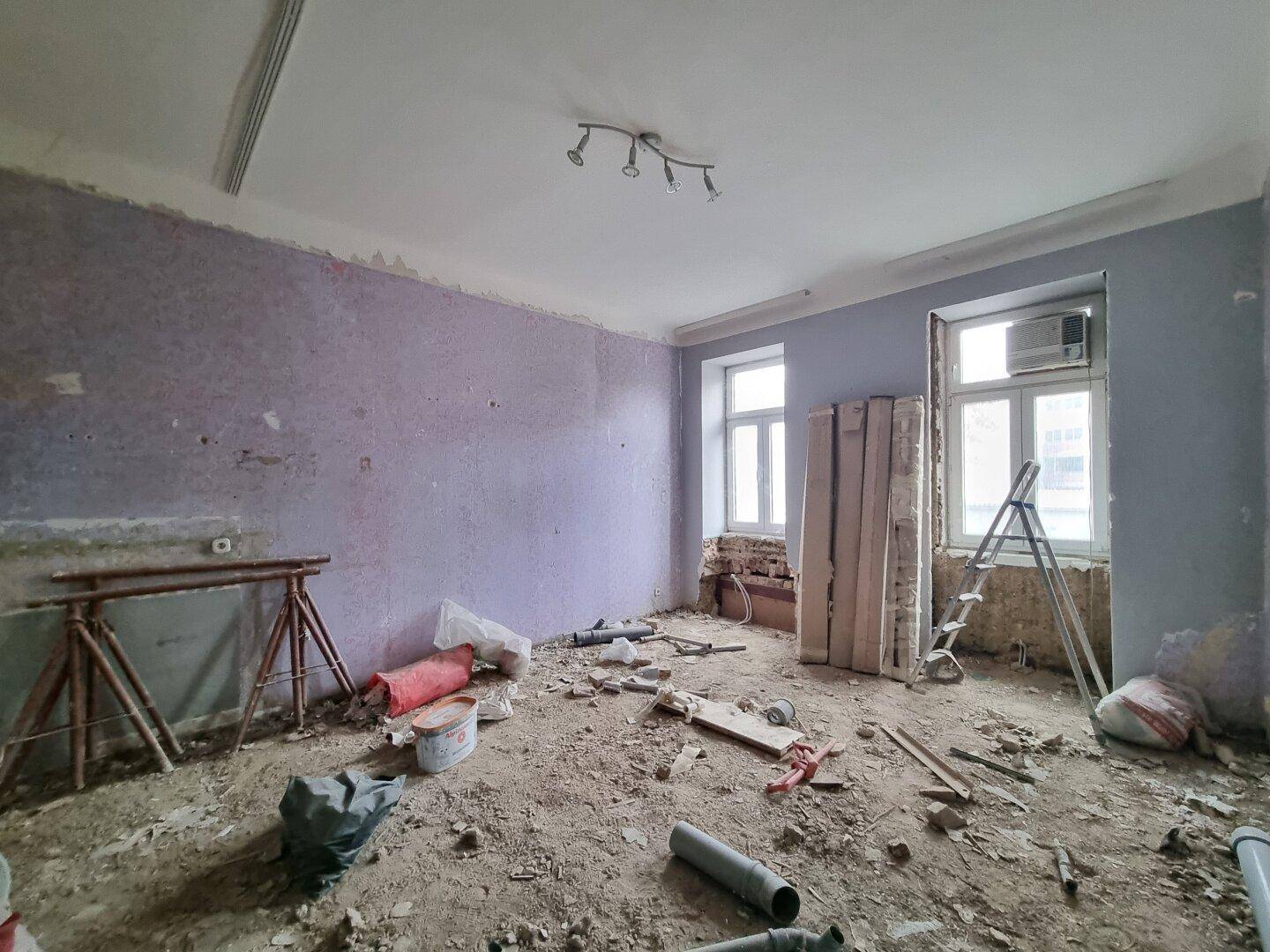 Renovierungsbedürftiger Raum mit abgenutzten Wänden und Baumaterialien, bereit für die Sanierung.
