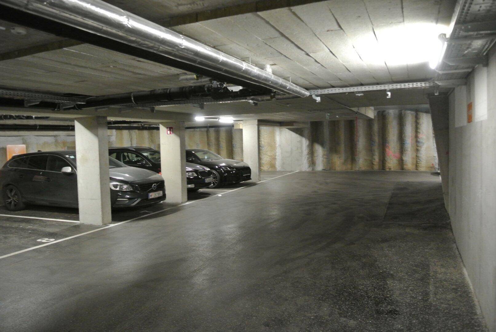 Tiefgarage mit mehreren geparkten Autos und Betonstützen, bietet sichere Stellplätze.