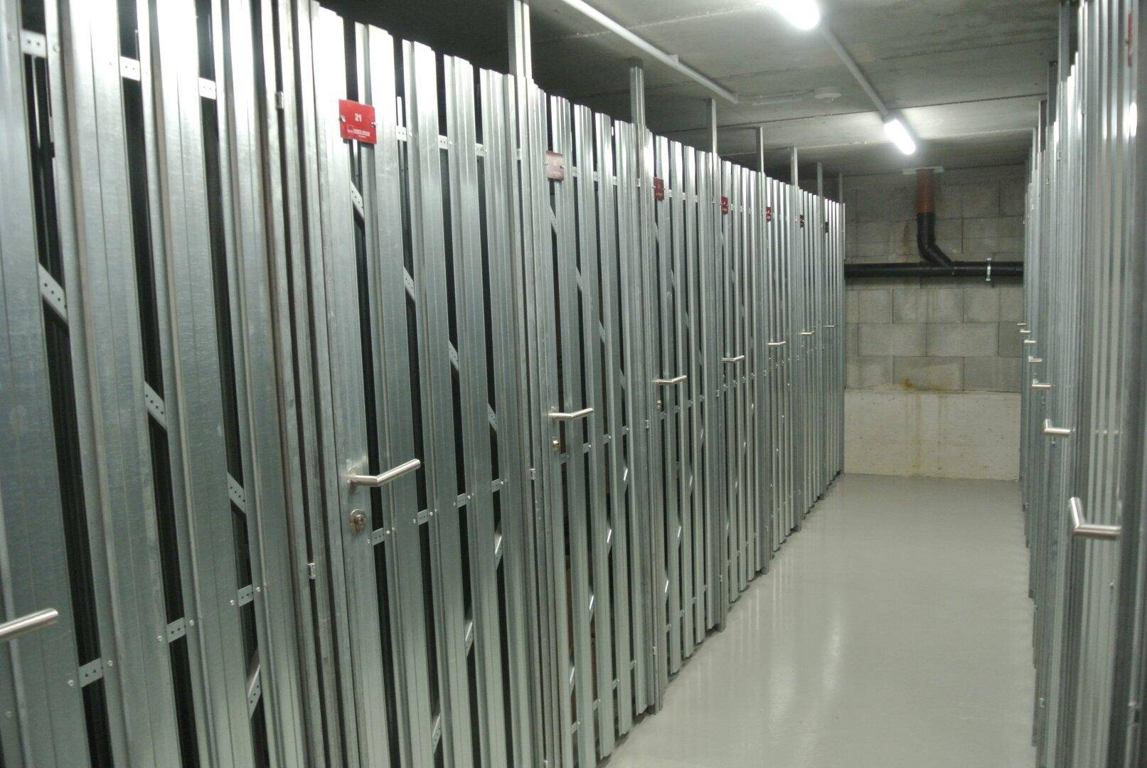 Geräumiger Kellerraum mit vielen einzelnen Abteilen aus Metallgittern für zusätzlichen Stauraum.