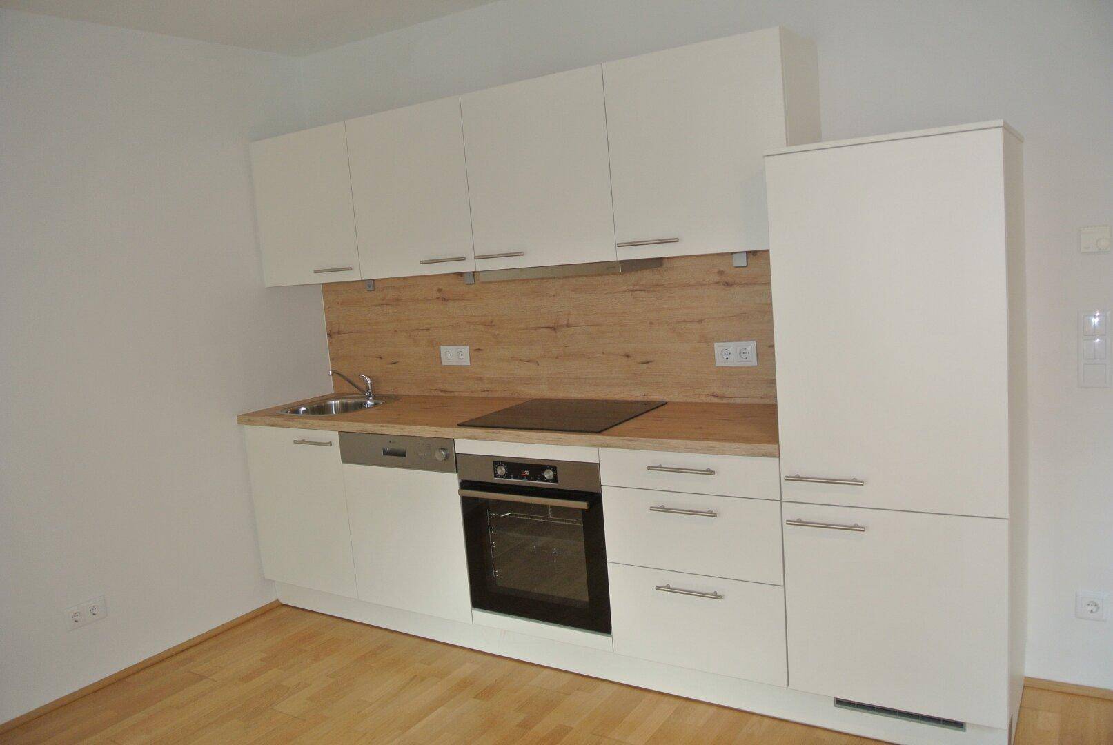 Moderne Einbauküche mit weißen Schränken, Holzoptik-Arbeitsplatte und integrierten Geräten.