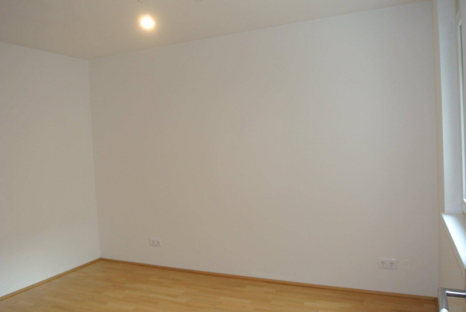 Leerer Raum mit hellem Holzboden und weißen Wänden, ideal für Schlafzimmer oder Büro.