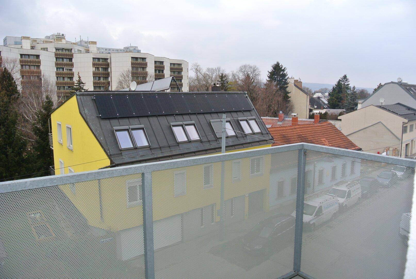 Blick von einem Balkon über Dächer mit Solaranlagen und umliegende Wohngebäude.