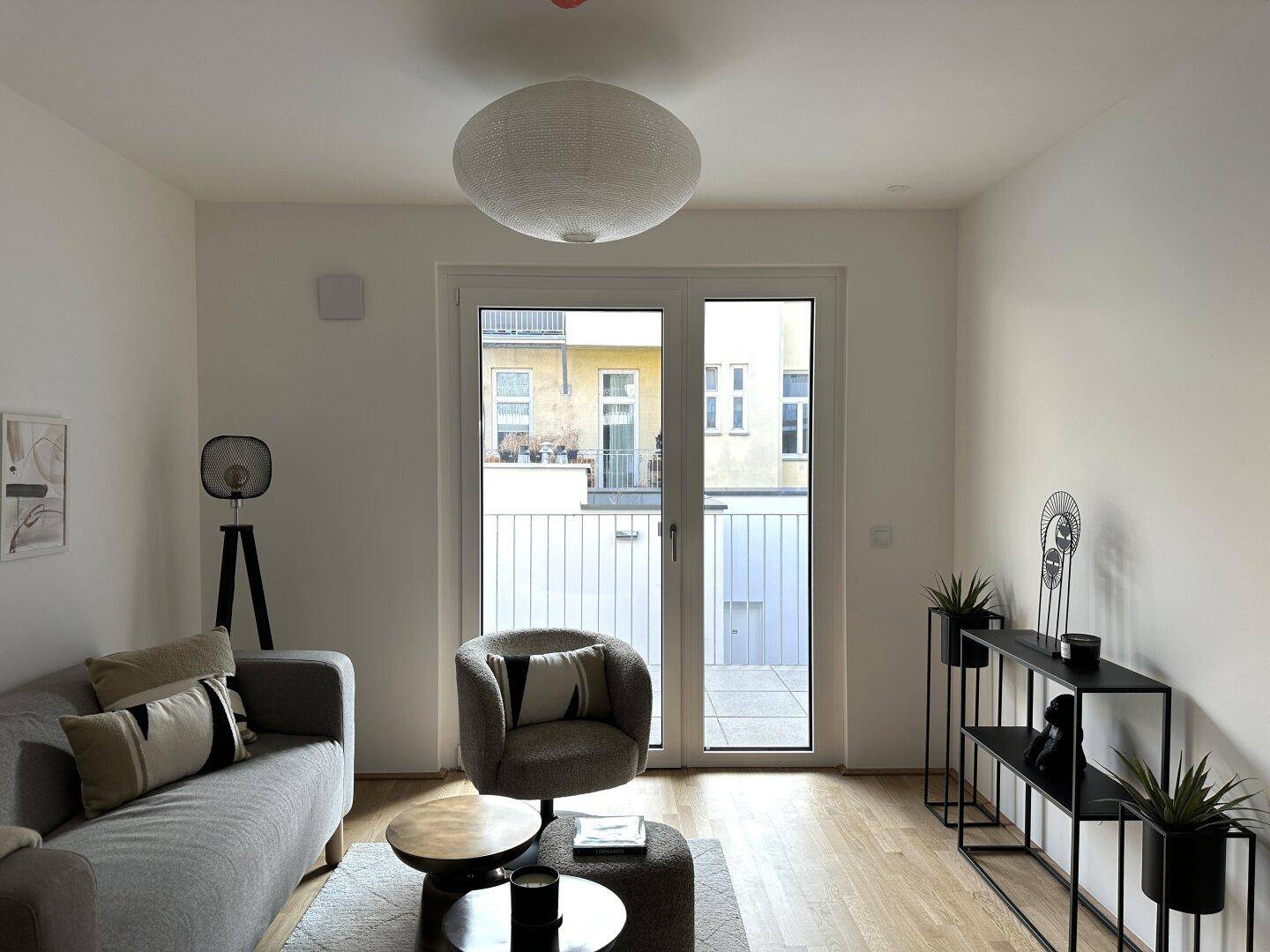 Heller Wohnbereich mit Zugang zu einem Balkon und moderner Einrichtung.