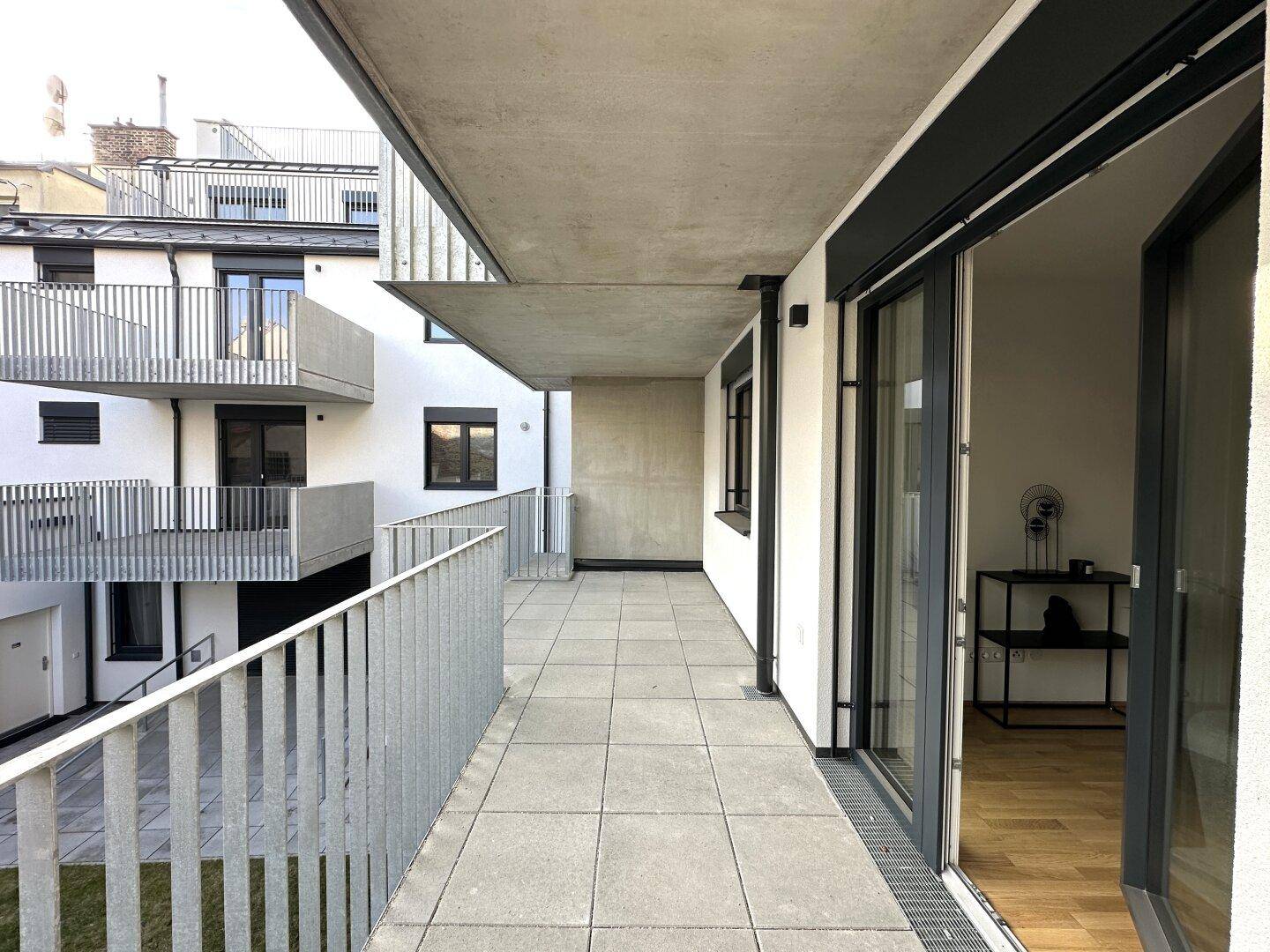 Geräumiger Balkon mit Fliesenboden und Blick auf die umliegenden Gebäude.