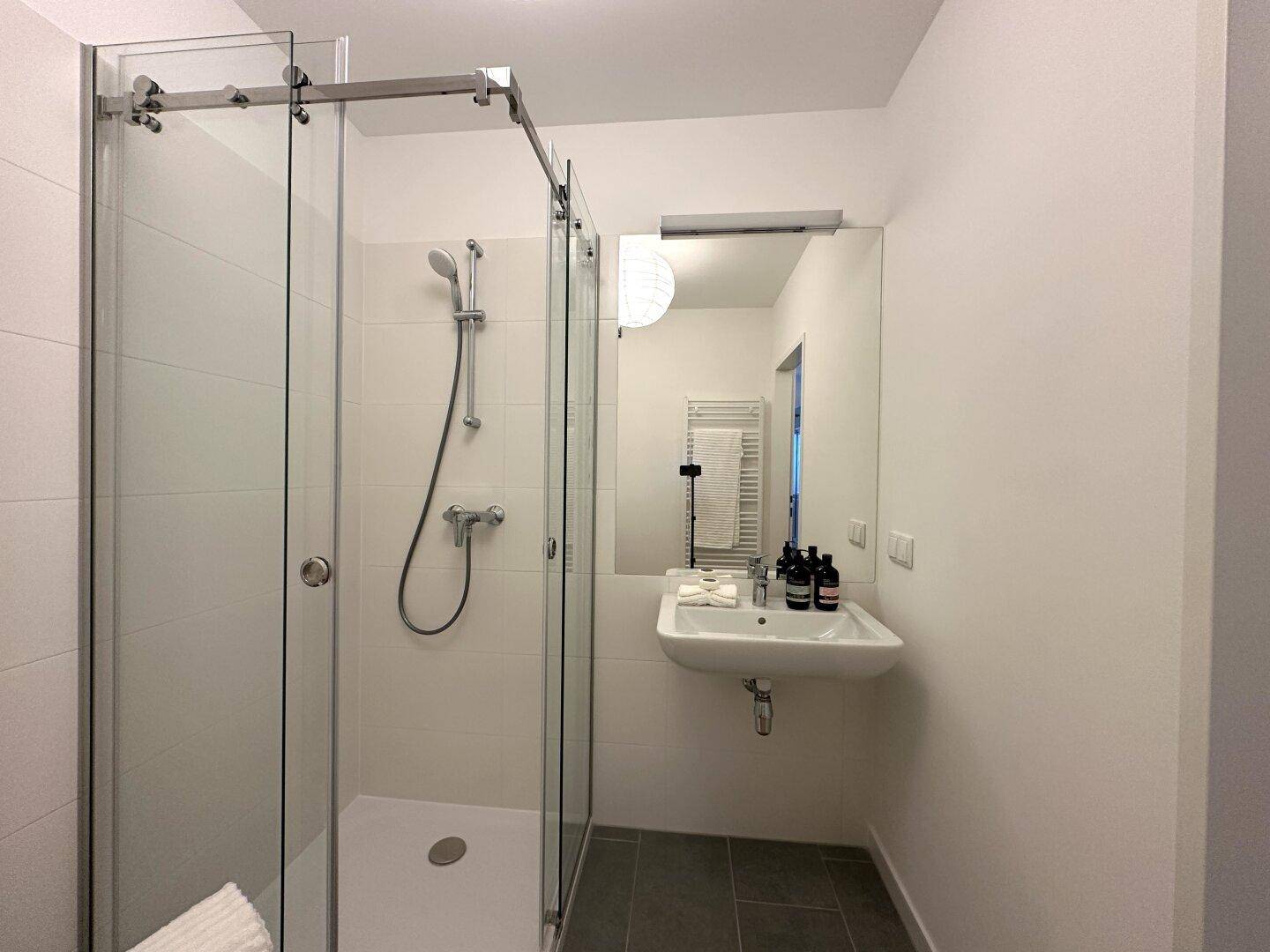 Helles Badezimmer mit moderner Duschkabine und Waschbecken.