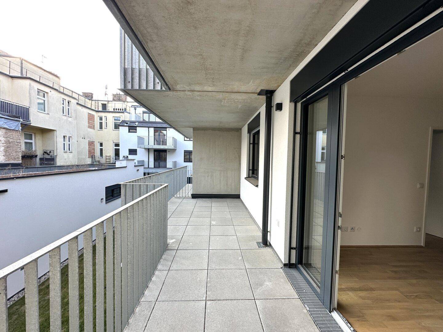 Geräumiger Balkon mit Fliesenboden und Metallgeländer, bietet Platz im Freien.