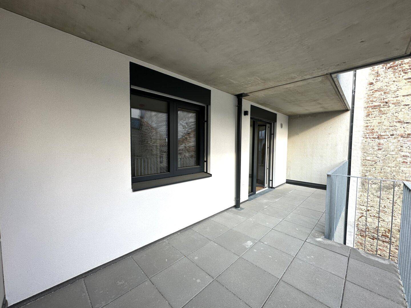Langer Balkon mit Fliesen und Blick auf die umliegenden Gebäude.