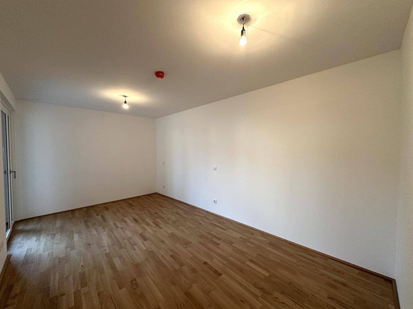 Leeres Schlafzimmer mit Parkettboden und weißen Wänden, bereit zur Einrichtung.