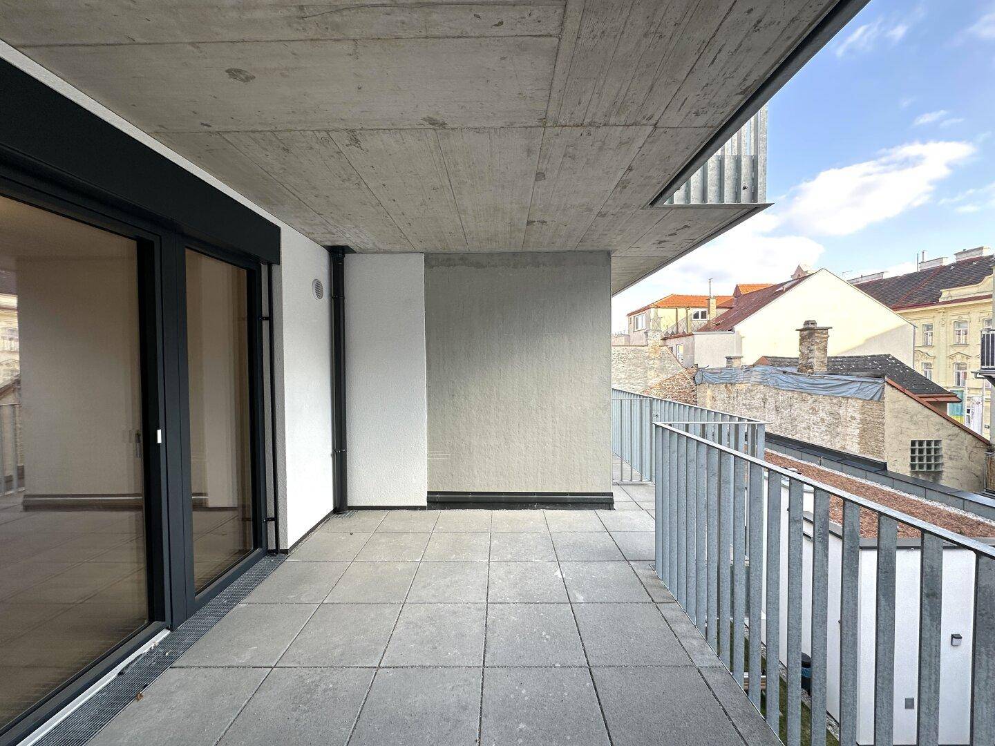 Geräumiger Balkon mit Fliesenboden und Blick auf die umliegenden Gebäude.