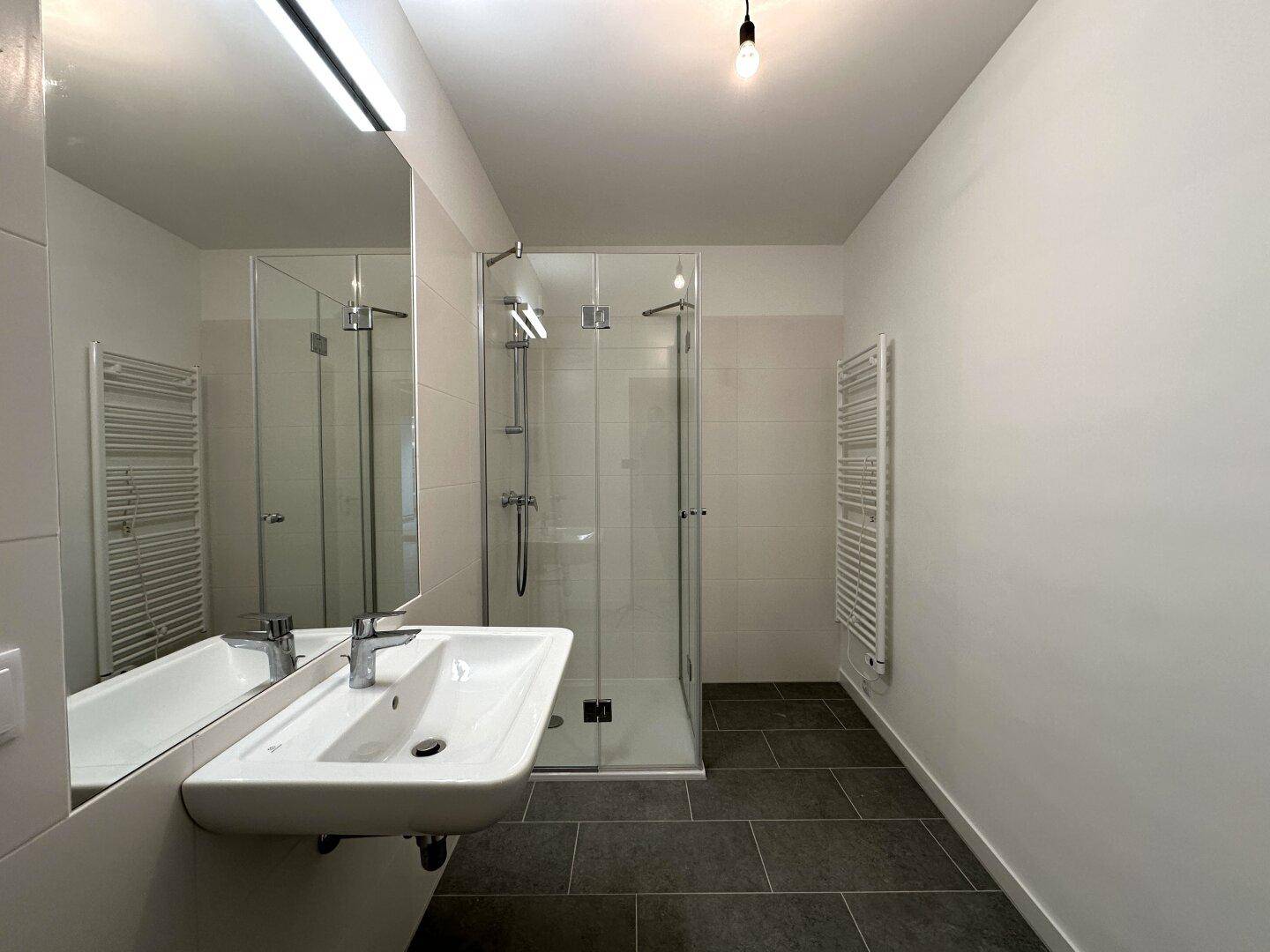 Helles Badezimmer mit Duschkabine, modernem Waschbecken und Fliesenboden.
