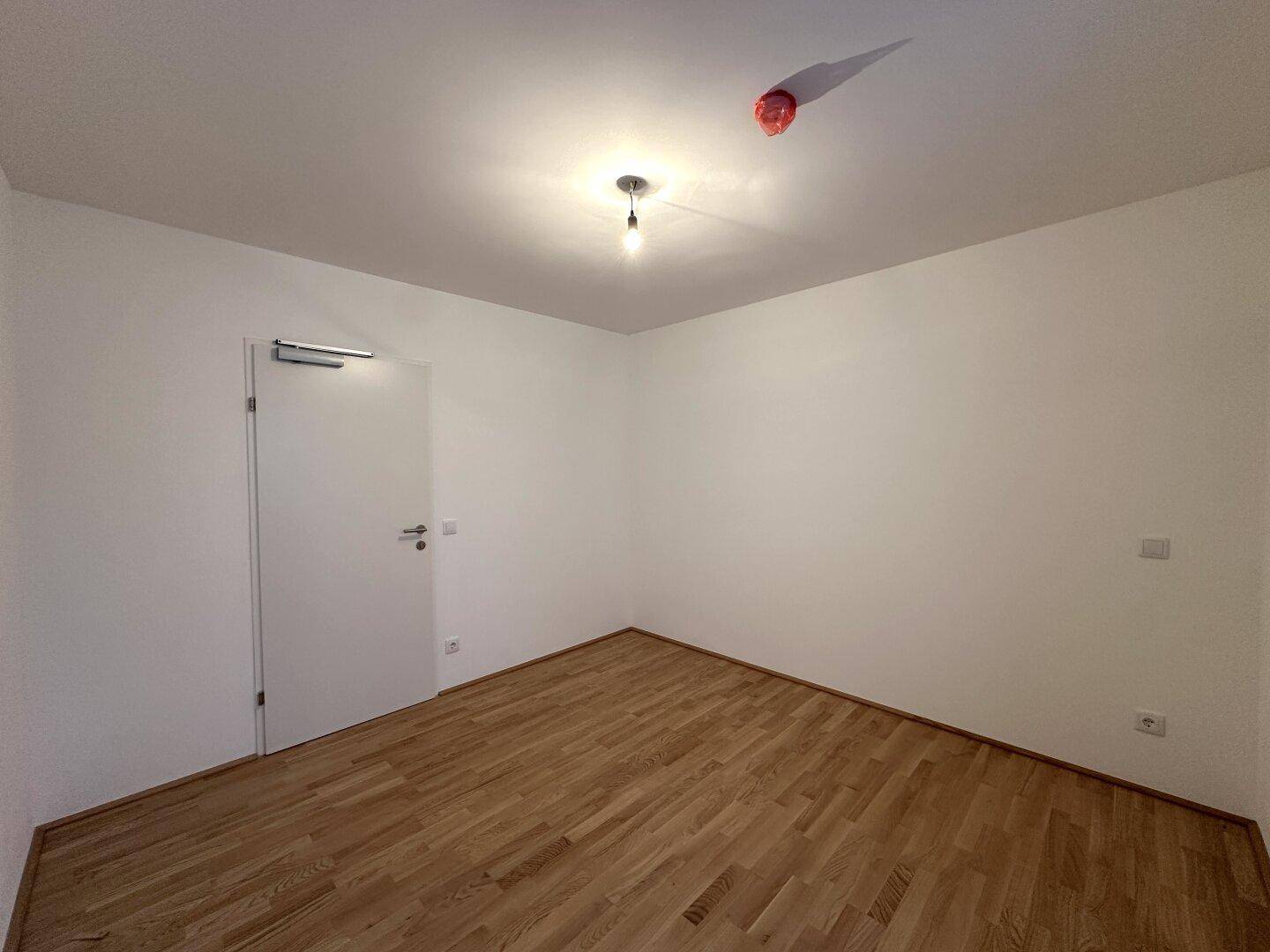 Ruhiges Zimmer mit Parkettboden und weißer Tür, bietet Privatsphäre und Komfort.