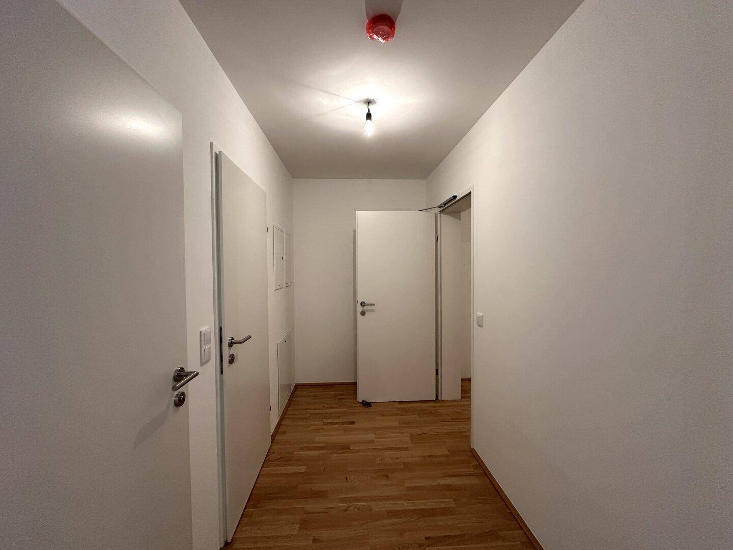 Langer Flur mit Parkettboden und mehreren Türen, verbindet die verschiedenen Räume der Wohnung.