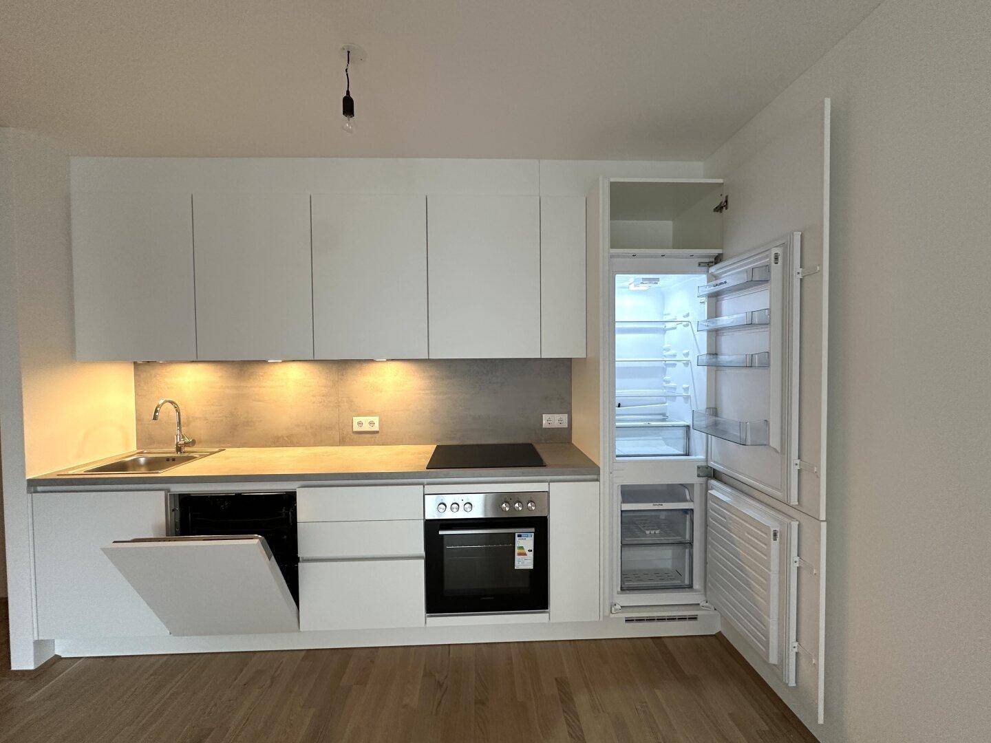 Voll ausgestattete moderne Küche mit weißen Fronten, Kühlschrank und Geschirrspüler.
