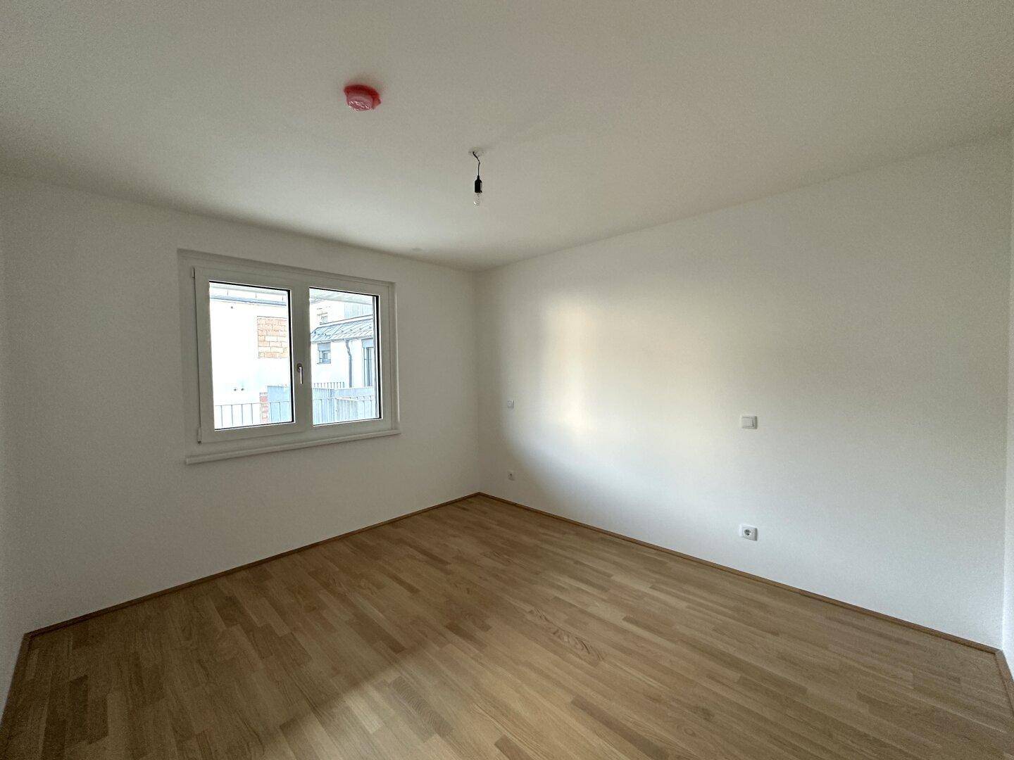 Geräumiges Schlafzimmer mit Parkettboden und Fenster, ideal für individuelle Einrichtung.