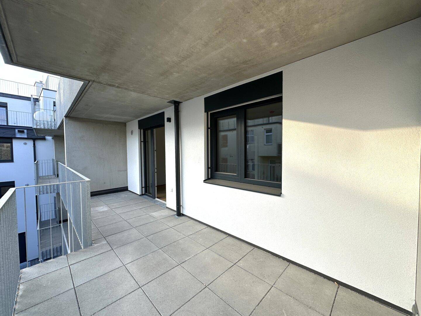 Geräumiger Balkon mit Fliesenboden und Zugang zum Innenbereich.