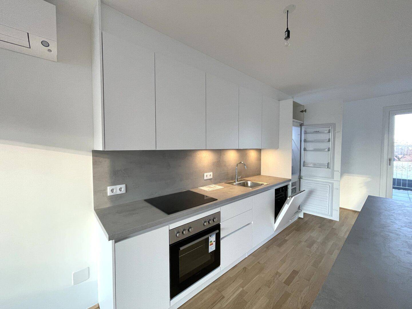 Voll ausgestattete moderne Küche mit integriertem Geschirrspüler und Kühlschrank, ideal für den Erstbezug.