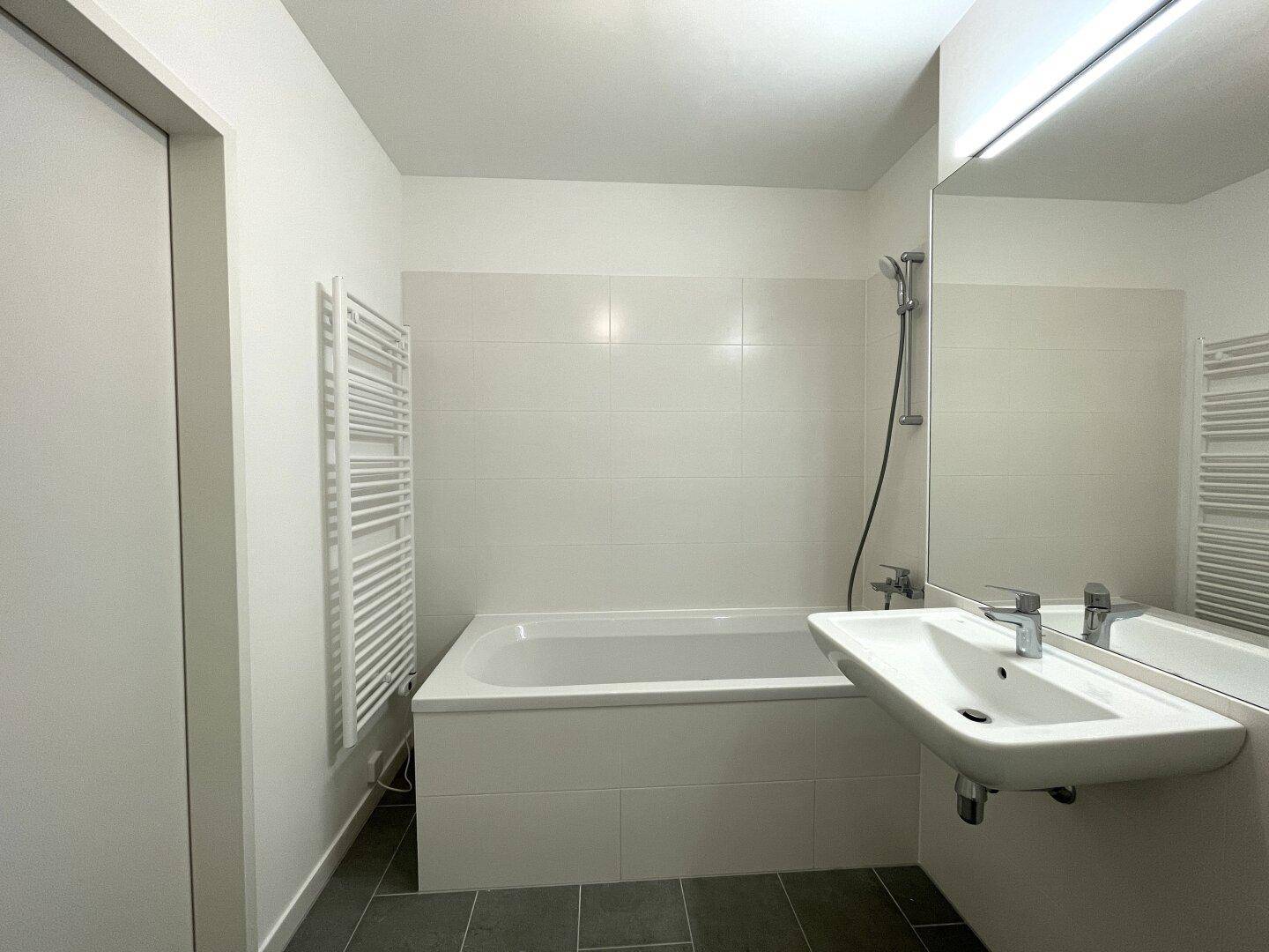 Geräumiges Badezimmer mit Badewanne und einem praktischen Handtuchheizkörper, in modernem Design.