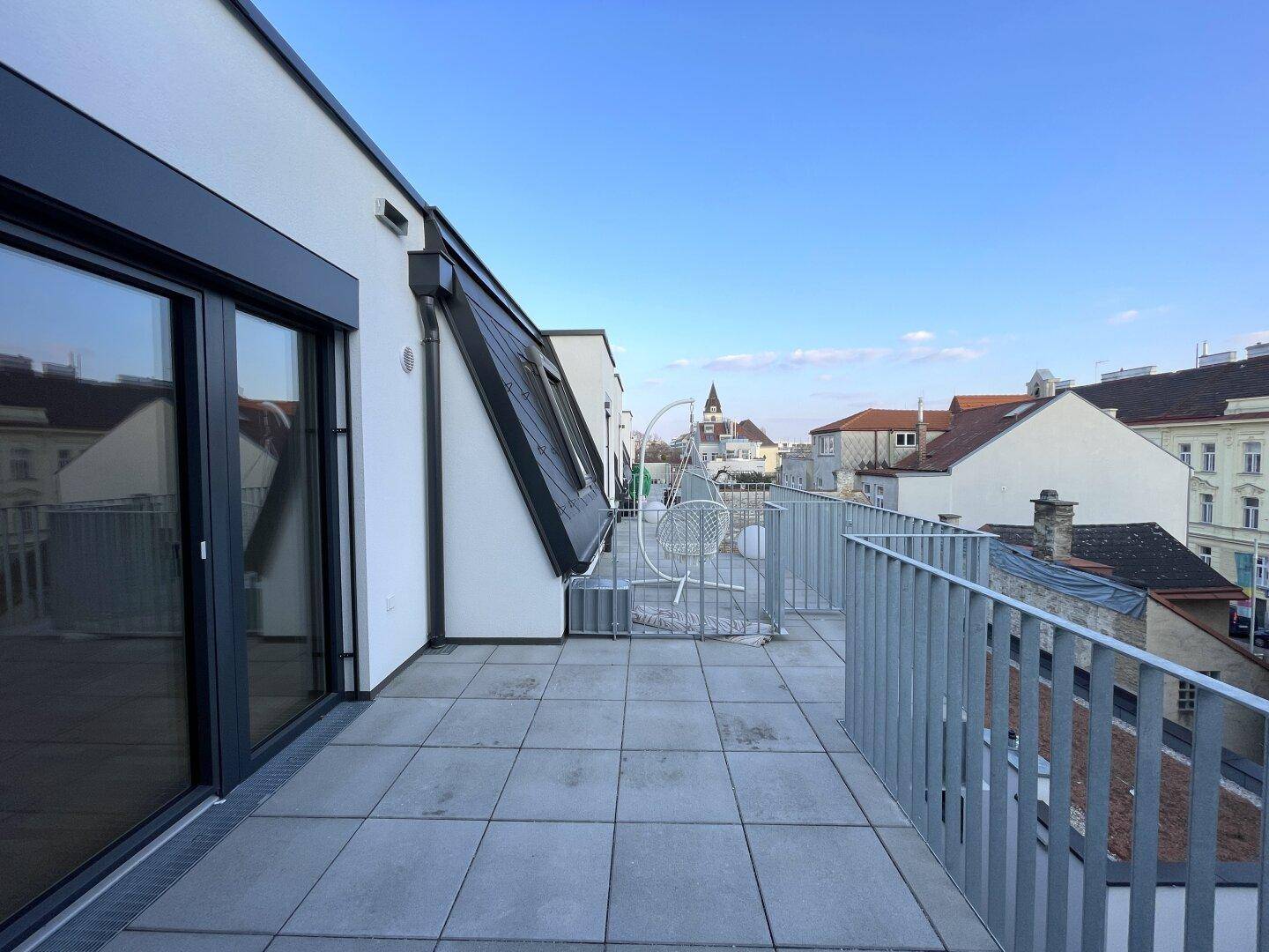 Geräumige Dachterrasse mit Fliesenboden und weitem Blick über die Stadt.