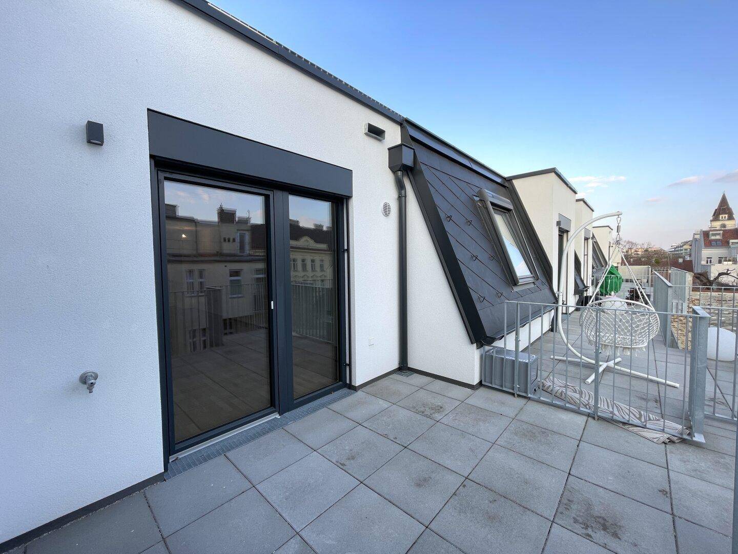 Sonniger Außenbereich auf der Dachterrasse mit moderner Architektur und Stadtblick.