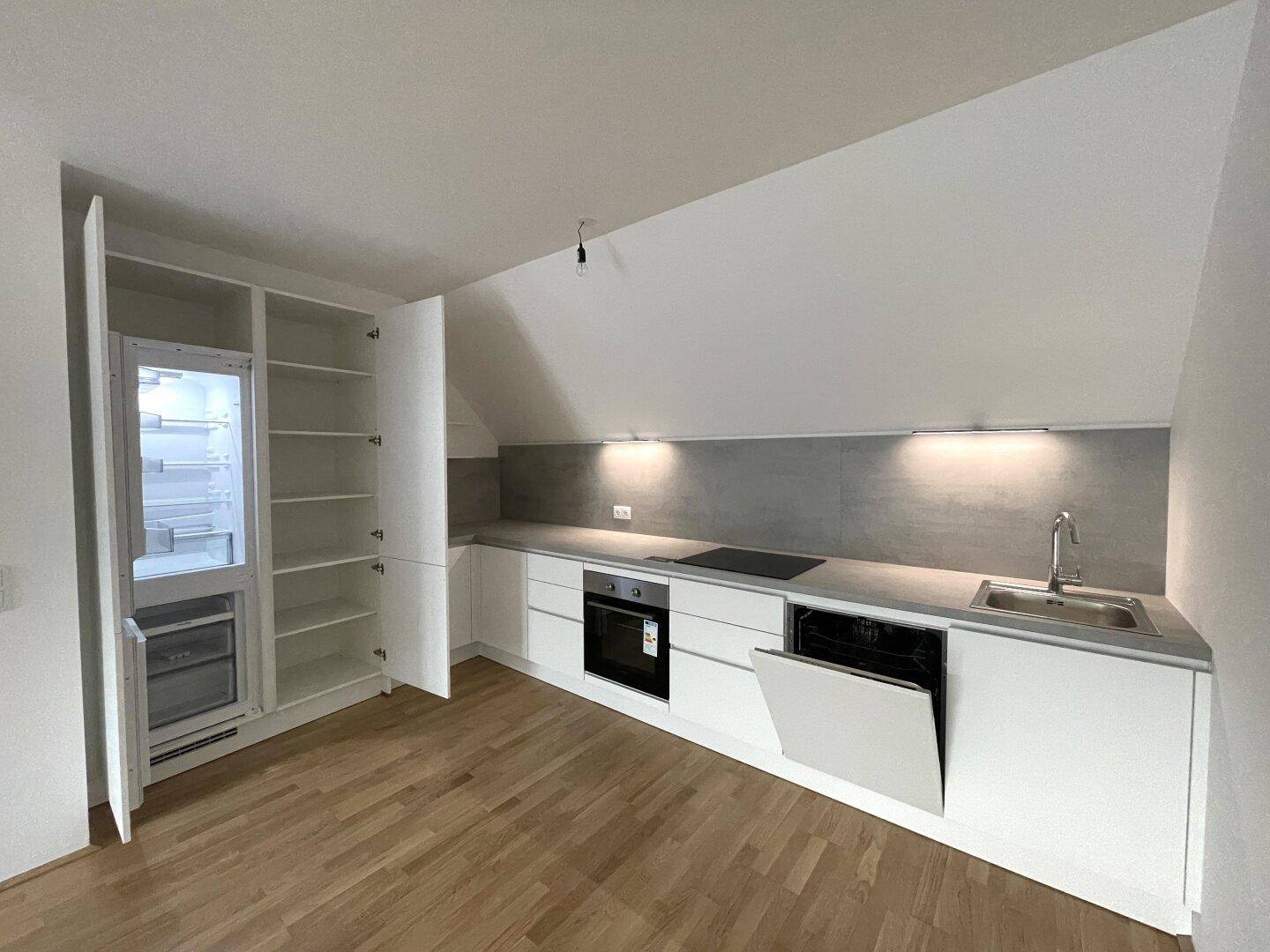 Voll ausgestattete, moderne Küche mit weißen Fronten, Kühlschrank und Geschirrspüler.
