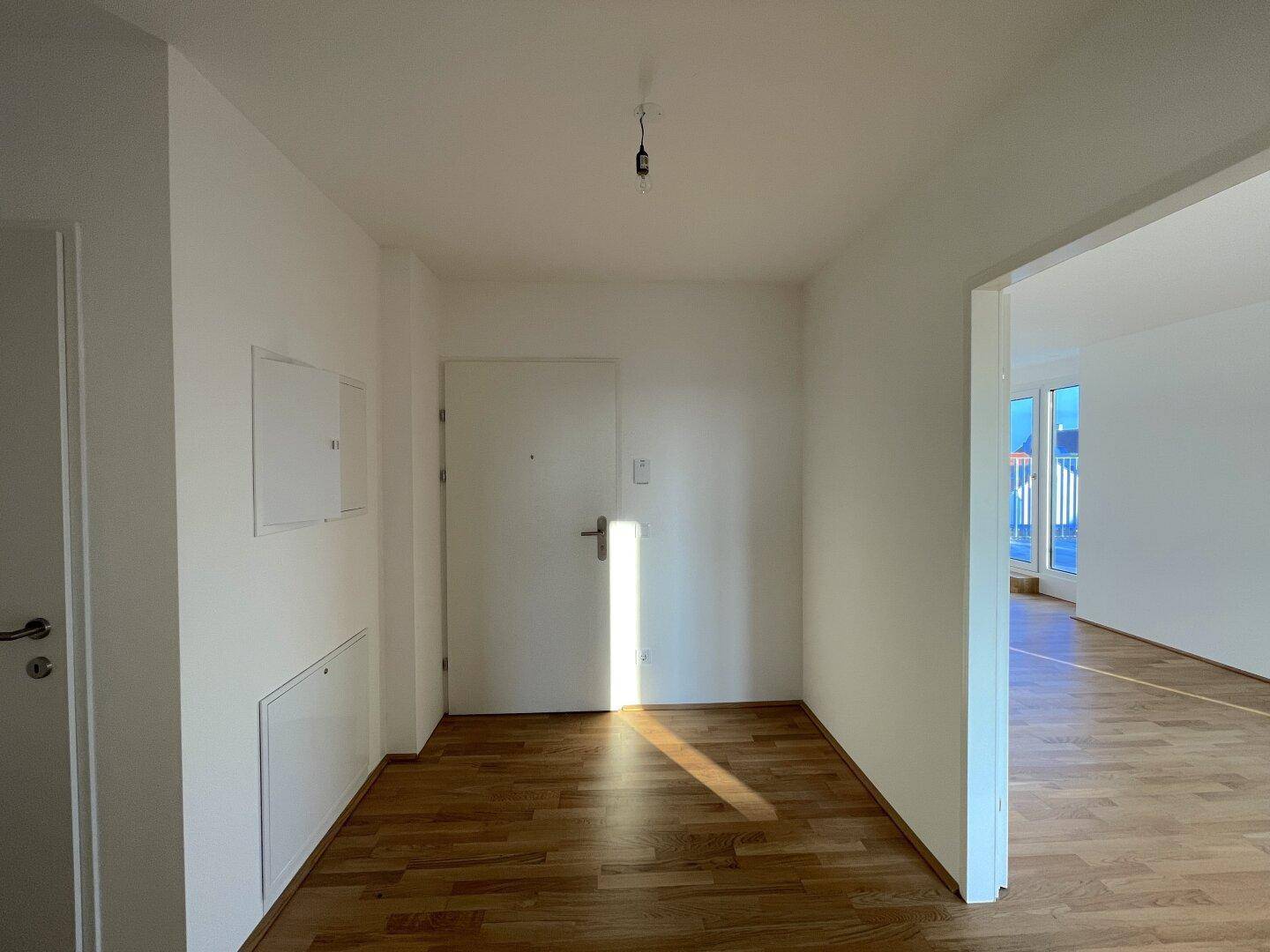 Heller Eingangsbereich mit Holzboden und weiß gestrichenen Wänden, einladend und funktional.