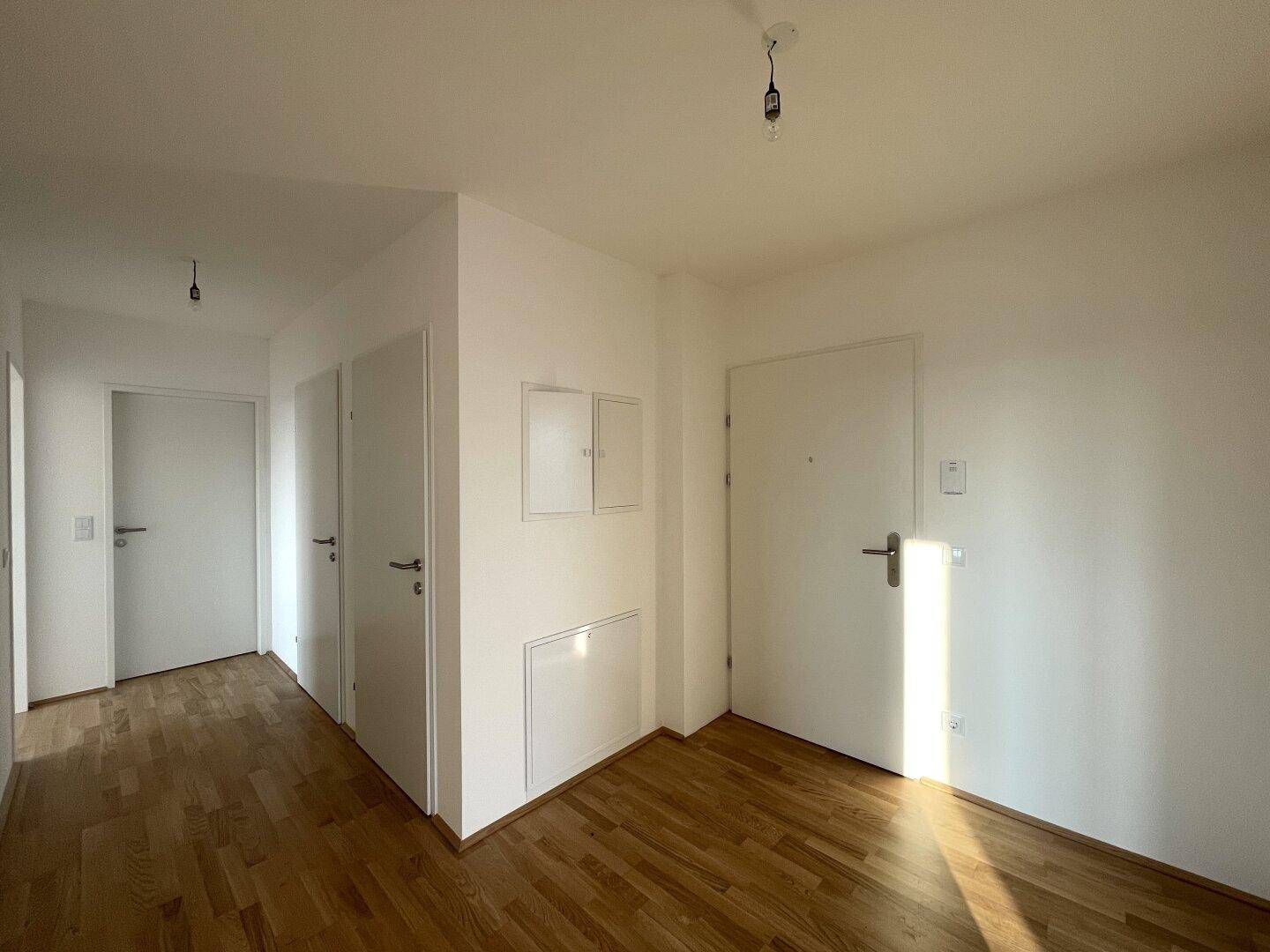 Heller Flur mit Holzboden und mehreren Türen, der zu den verschiedenen Räumen führt.