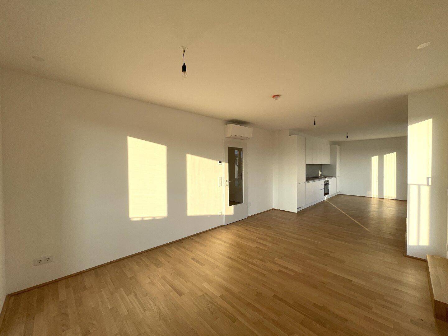 Geräumiges, lichtdurchflutetes Wohnzimmer mit Parkettboden und moderner Klimaanlage.