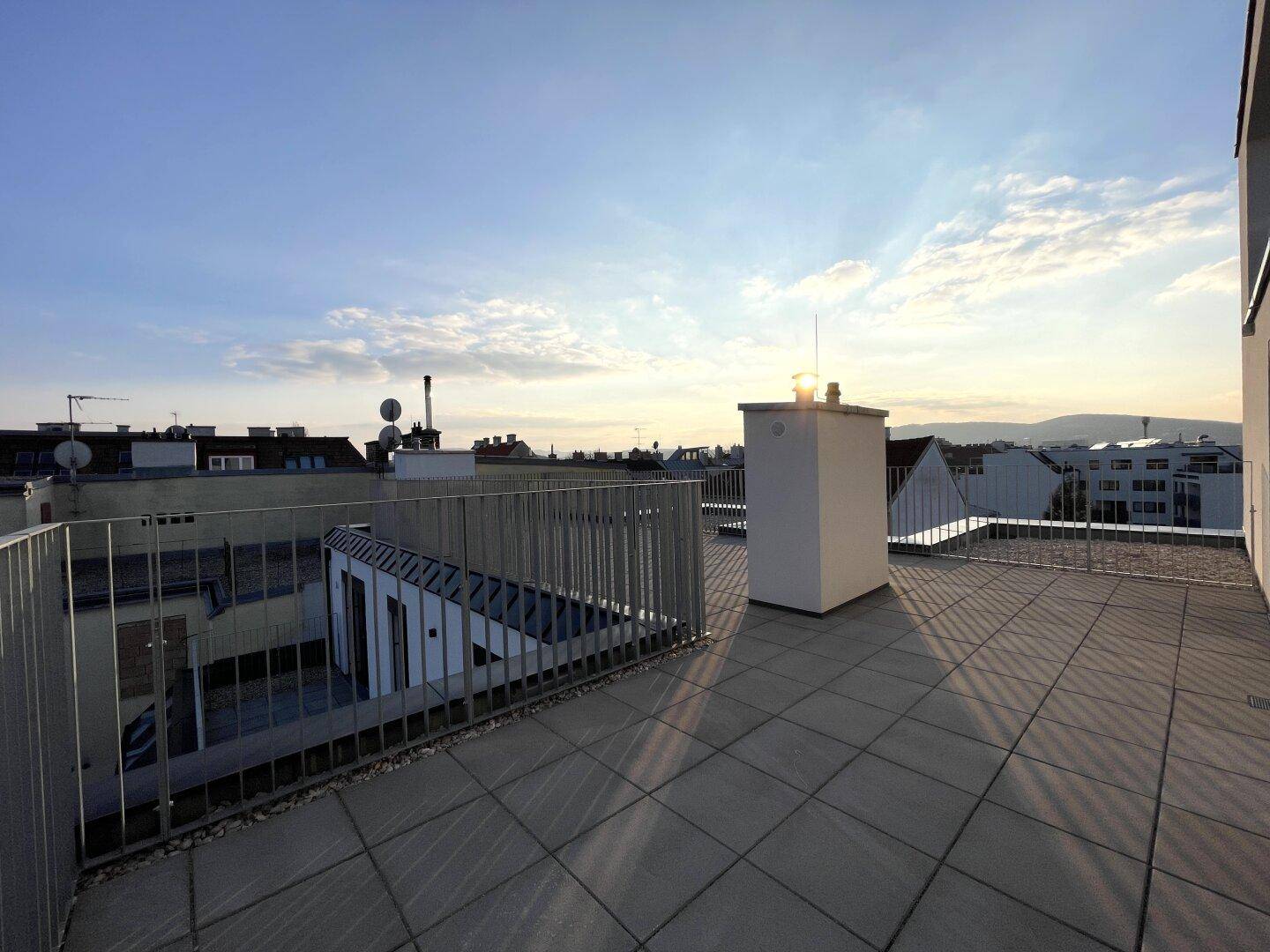 Geräumige Dachterrasse mit Fliesenboden und Panoramablick über die Stadt und Berge.