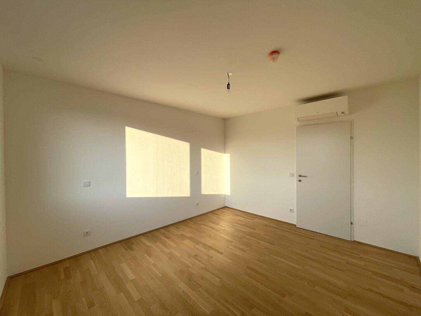 Geräumiges Schlafzimmer mit Parkettboden, Klimaanlage und viel natürlichem Licht.