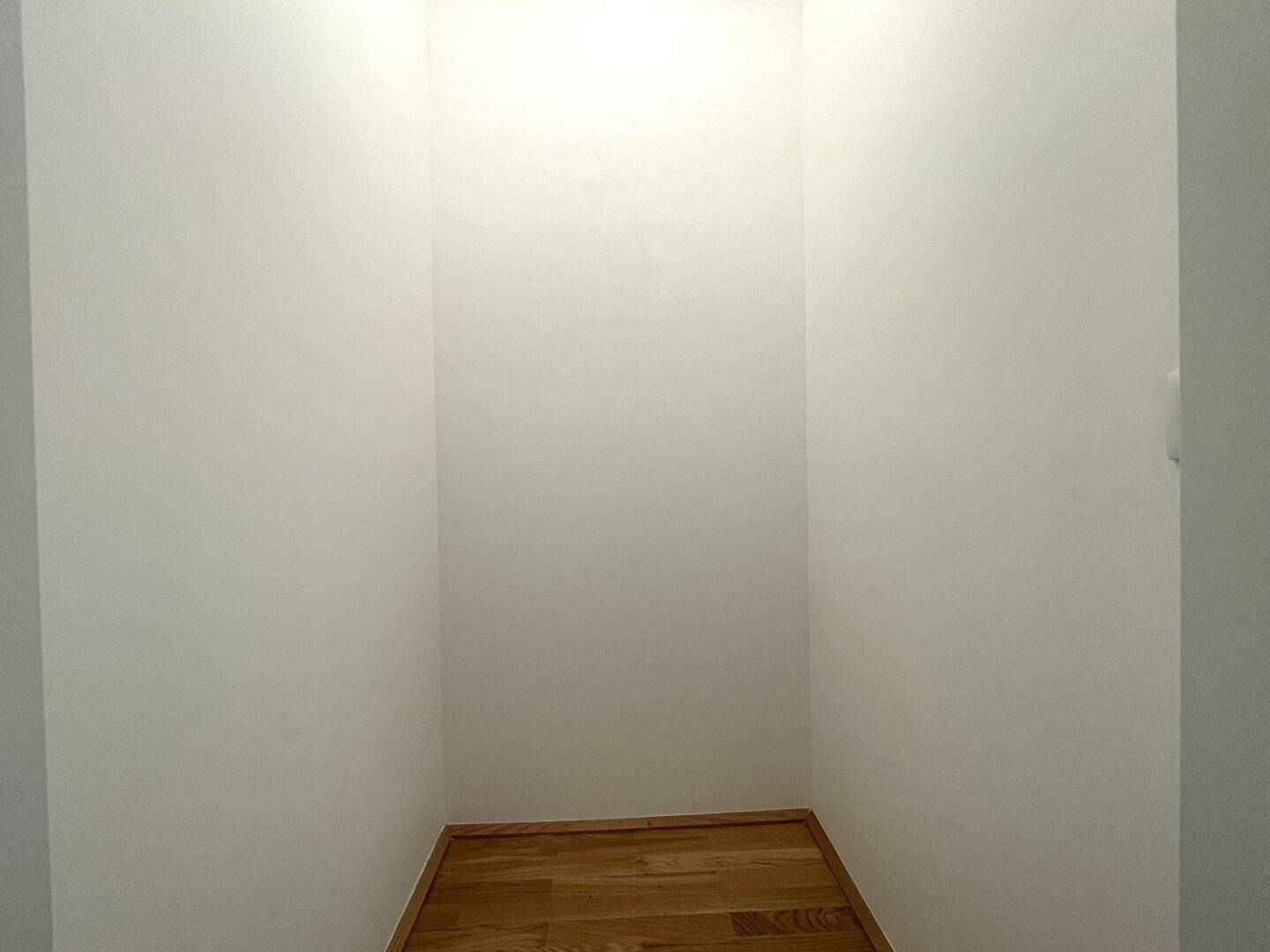 Kleiner, leerer Raum mit hellem Holzfußboden, ideal als Abstellraum oder begehbarer Kleiderschrank.