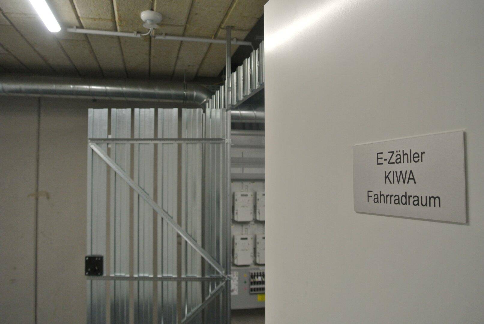 Gemeinschaftlicher Fahrradraum mit Metallabtrennungen und Elektrozählern im Untergeschoss.