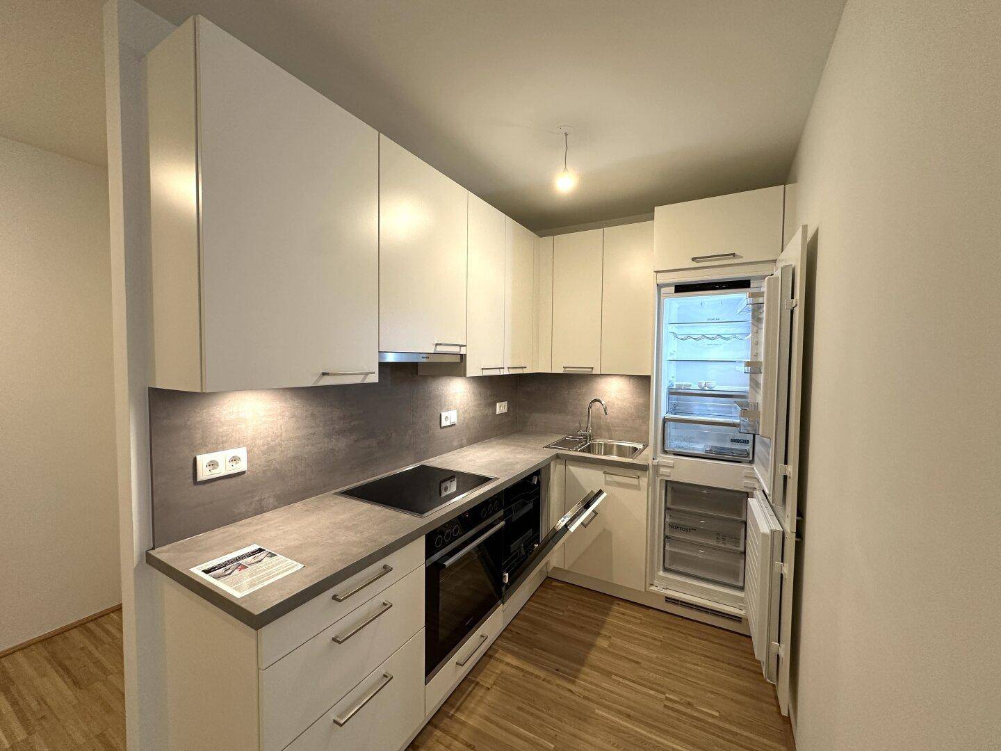 Voll ausgestattete, moderne Küche mit Kühlschrank, Backofen und viel Stauraum.