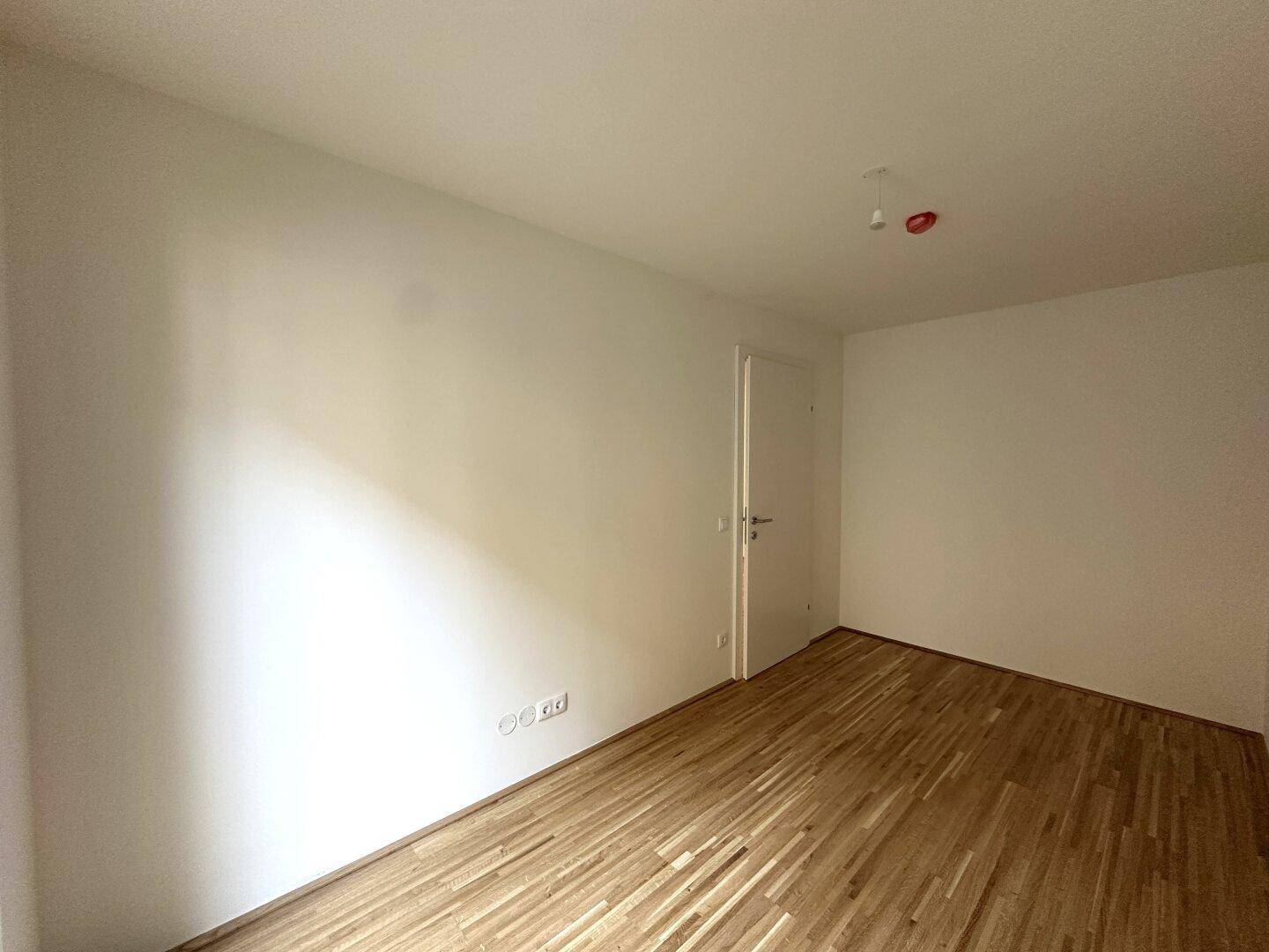 Helles Schlafzimmer mit Parkettboden und weißer Tür, ideal für individuelle Gestaltung.