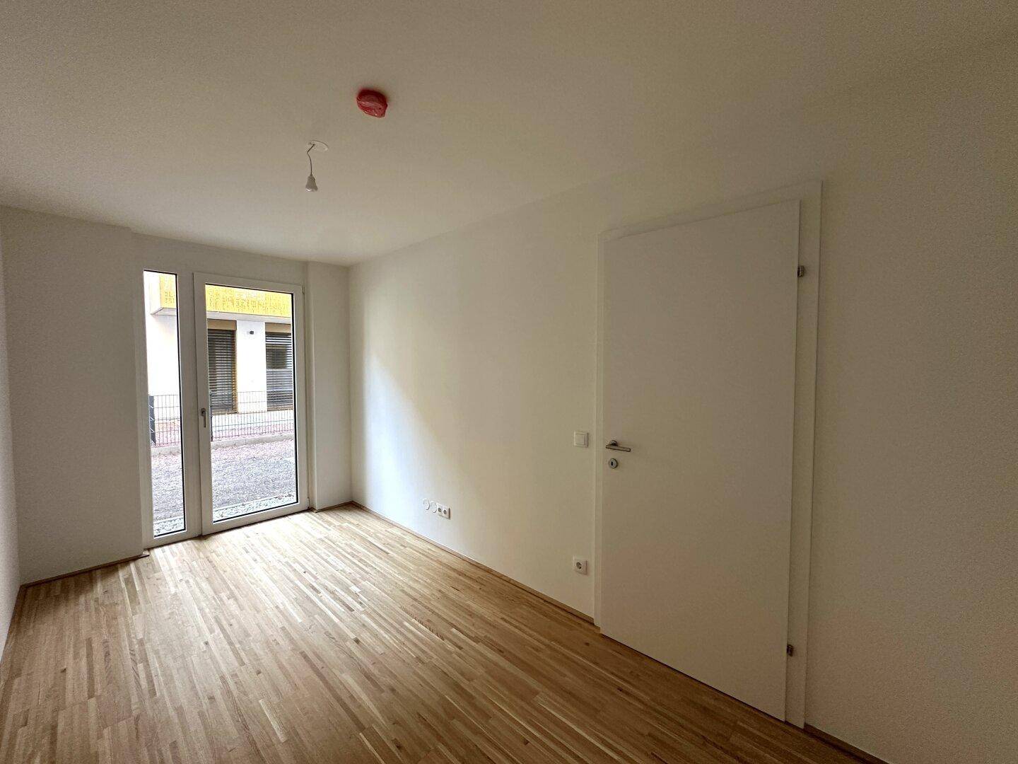 Schlafzimmer mit Parkettboden und direktem Zugang zu einer Außenterrasse.