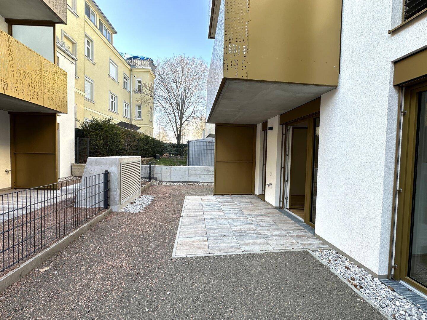 Kleine gepflasterte Terrasse im Erdgeschoss mit Zugang zum Gartenbereich.