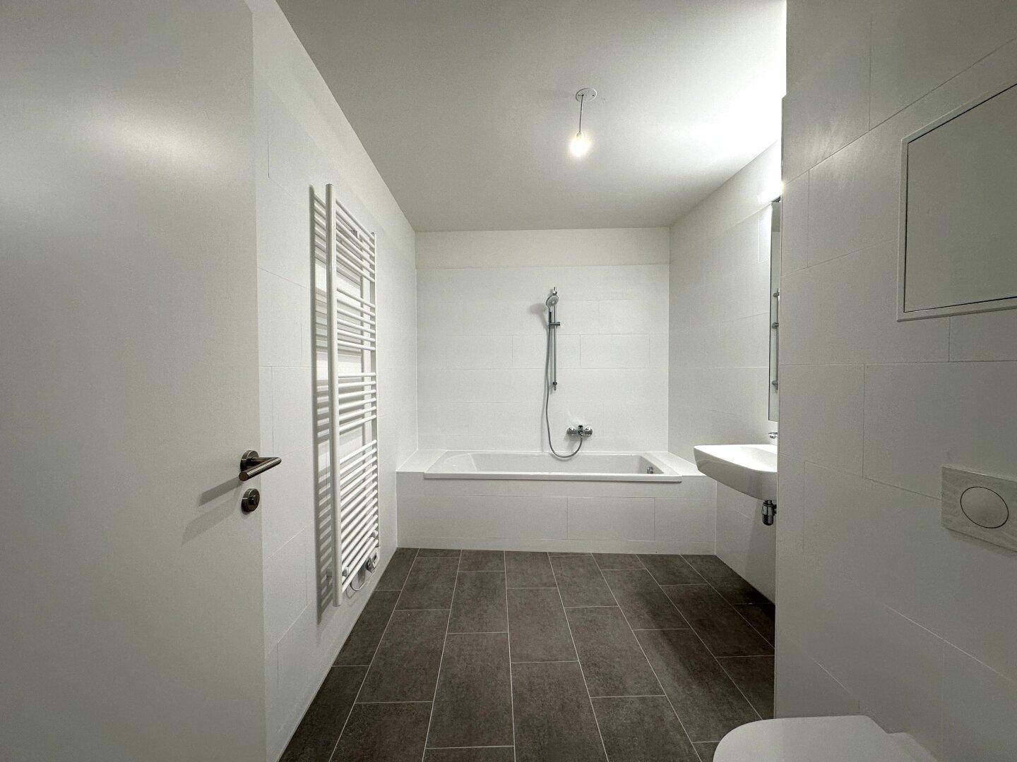 Modernes Badezimmer mit Badewanne, Waschbecken und Handtuchheizkörper.