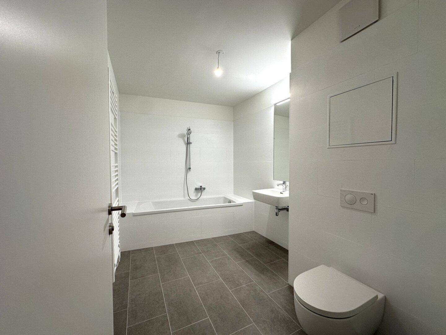 Helles Badezimmer mit Badewanne, WC und modernem Waschbecken.