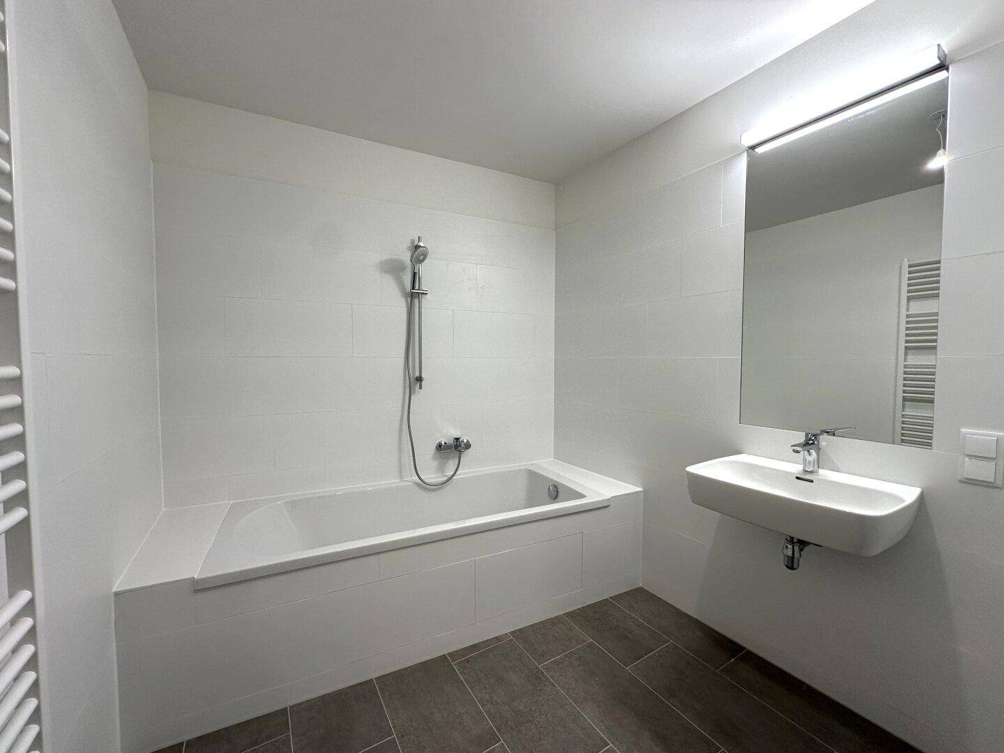 Modernes Badezimmer mit Badewanne, Spiegel und schlichtem Design.